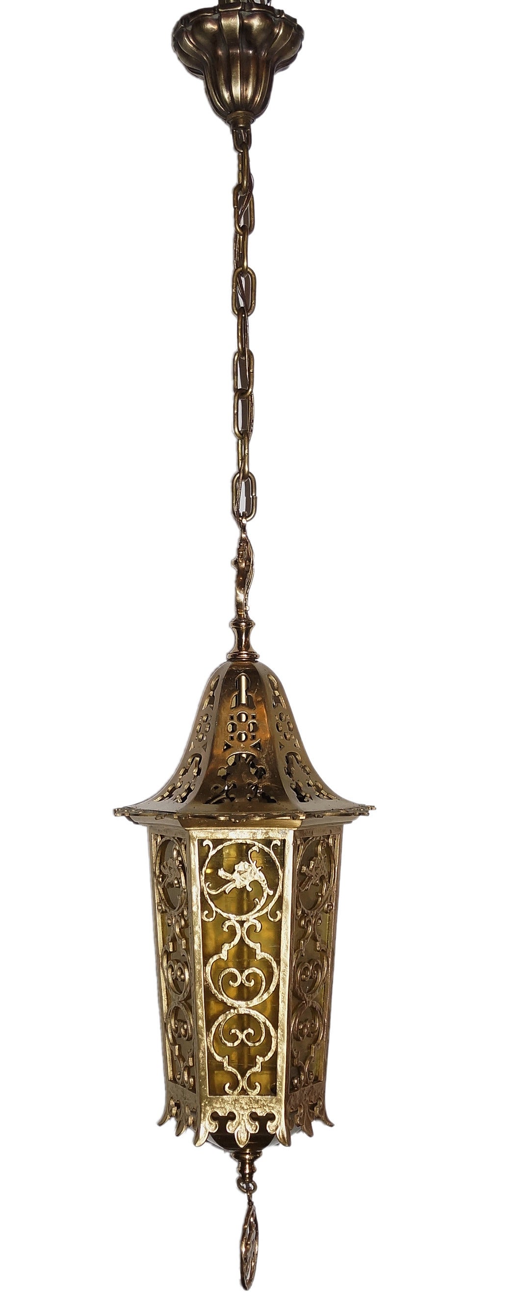 Circa 1925 Neo-Gothic style bronze interior lantern of hexagonal form, having filigree and tracery design and inverted fleur de lis pattern. Lantern is surmounted by a paired dragon finial. Dragon motif is continued in the tracery and the pendant