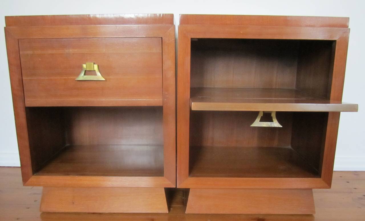 Vintage pair of Mid-Century Nightstands with brass pulls in the style of James Mont. Beautiful nightstands with ample storage space. Door pulls down. Shelf below. Detailed brass pull. Slight symmetrical angle to the base. Solid wood. Item available