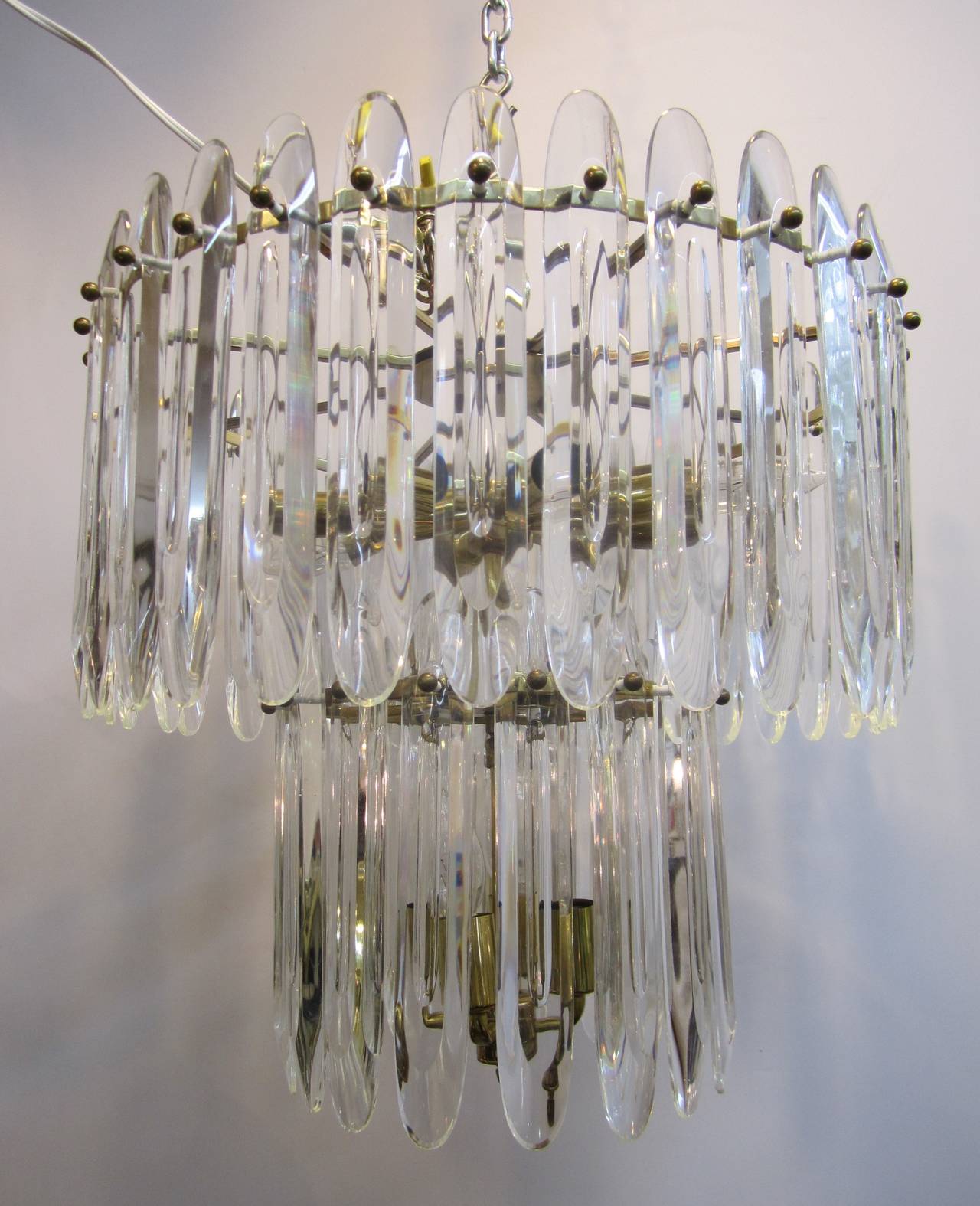 Lustre italien en cristal et laiton du designer Gaetano Sciolari, milieu du 20e siècle, vers les années 1960, Italie. Le lustre est composé de longs cristaux aux coins arrondis, à deux niveaux, avec des douilles de 12 lampes, sur un cadre en laiton.