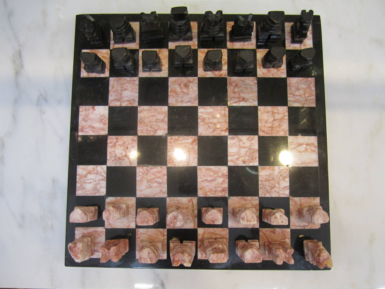 A beautiful 70s Modern Chess Set; a black and rose colored marble game board and black and rose colored onyx pieces. All pieces accounted for. Play chess or use as a decorative object or sculpture piece. Hand-made. Hand-carved. Perfect size of 10.5