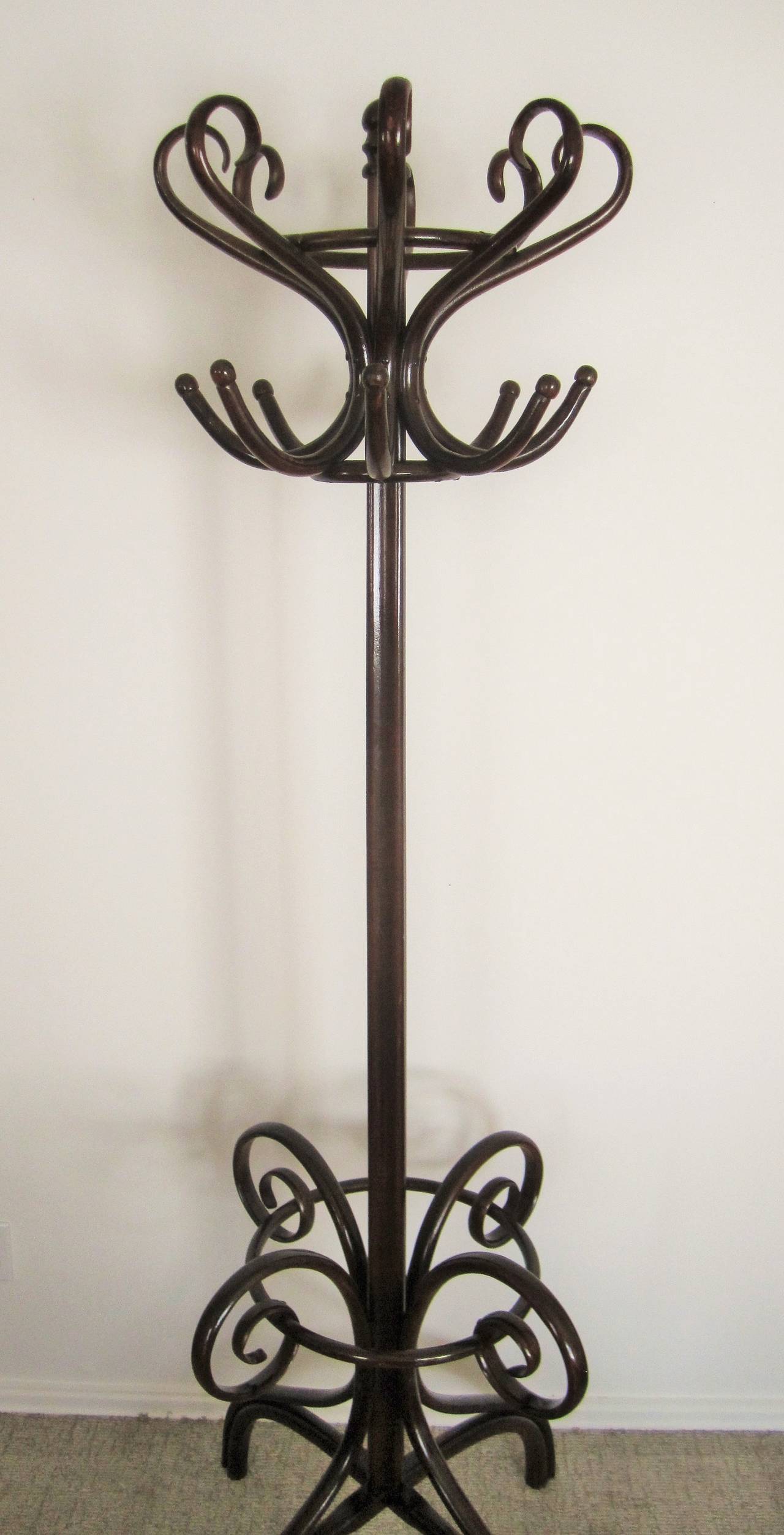 A beautiful and substantial vintage dark brown THONET bentwood coat rack or hall tree. Bentwood hall tree has 12 'hooks' at top, and a lower 'ring' base to hold umbrella's. Piece is 'By' or 'Attributed' to THONET. Piece is in very good vintage