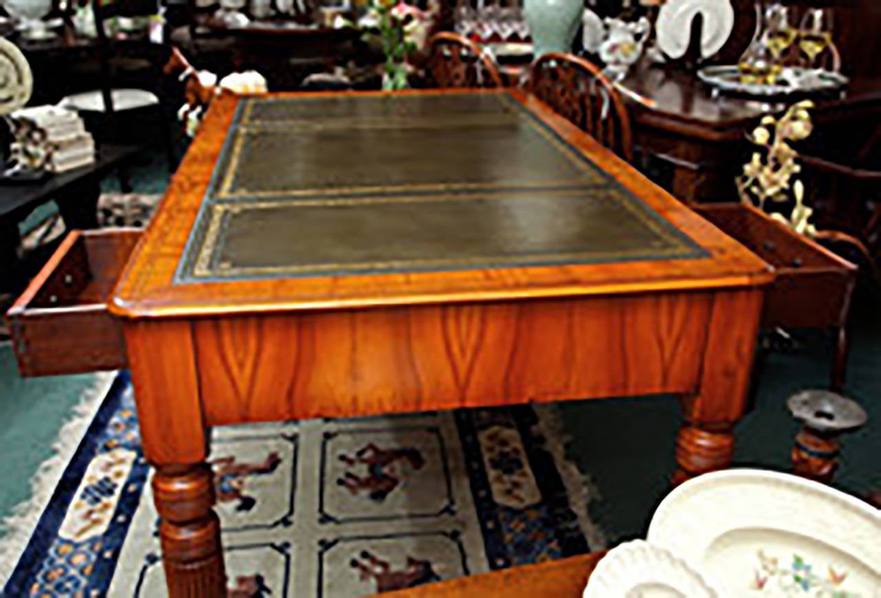 English yew wood partners desk with green leather top and gold tooling. Six drawers with three each side. Brass cup and castors. William IV style. Made in England, circa 1980.