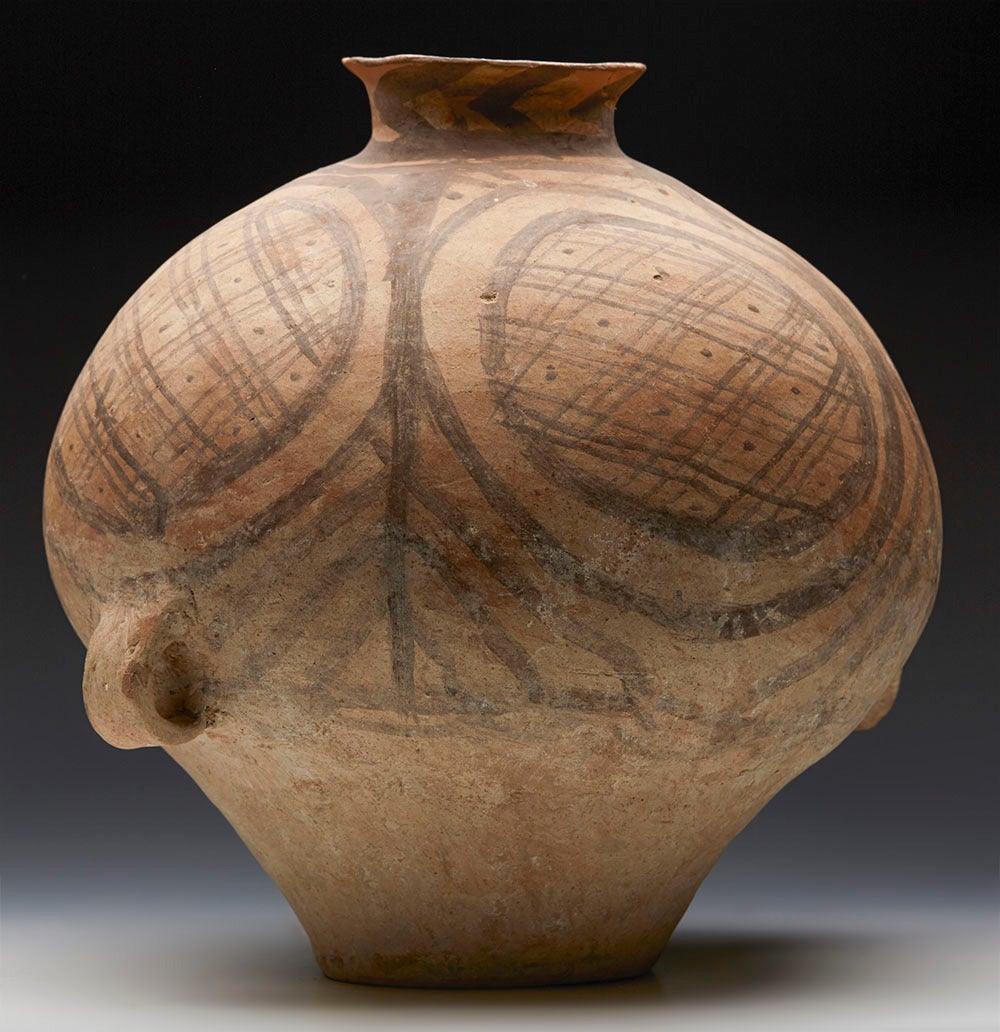 A Neolithic Chinese painted terracotta twin handled jar dating from the third millennium B.C. The earthenware jar has a bulbous form with two small loop handles attached to the lower body. The vase is painted with a horizontal band of cross hatched