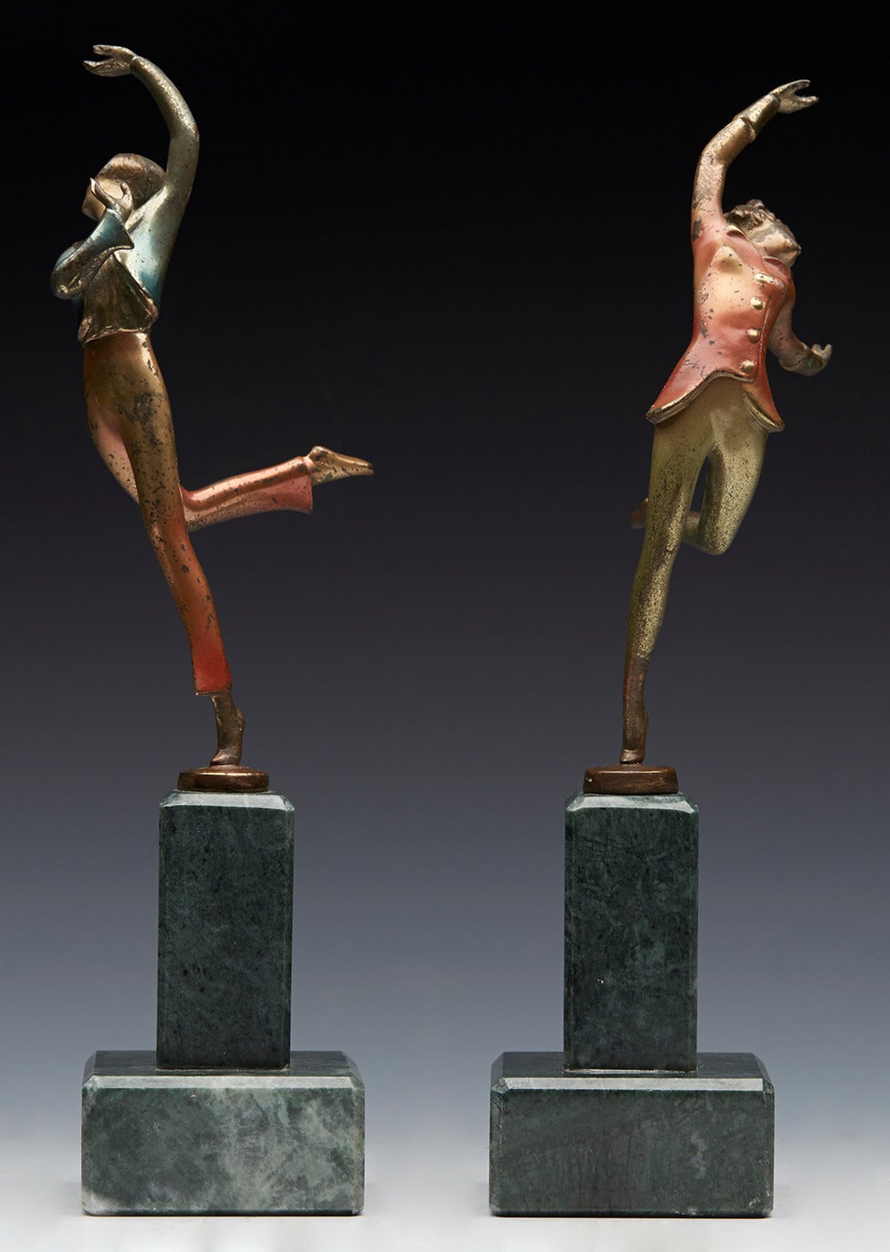 A pair of Art Deco cold painted bronze dancer figures by Austrian artist Josef Lorenzl and dating from around 1930. The figures are mounted on a polished stone column and each are cold painted in colored metallic glazes. They both have Lorenzl