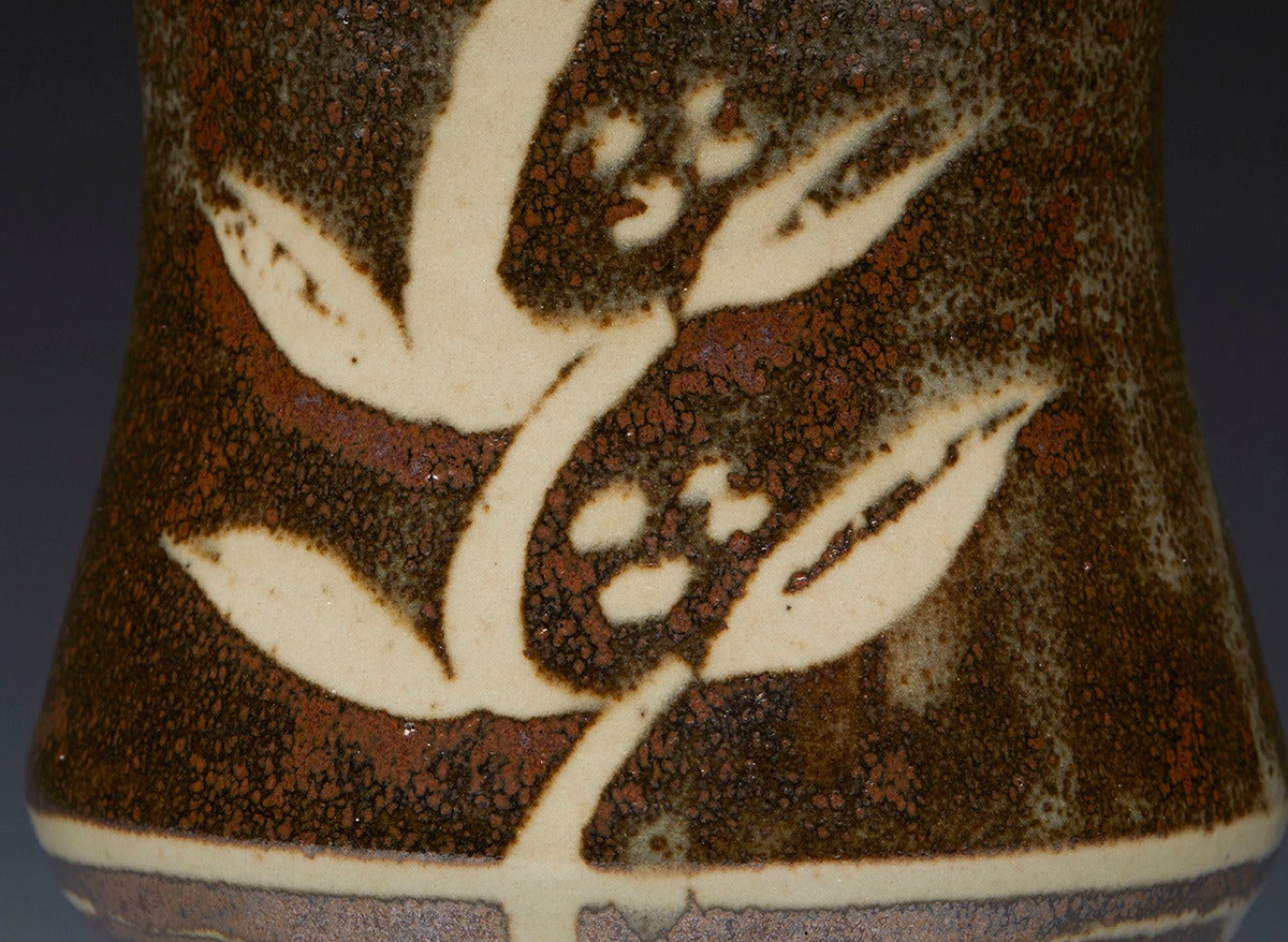 A very fine David Leach studio pottery stoneware vase. The vase is of albarello form and stands on a narrow rounded foot. It is decorated with foliate designs in mottled iron brown over cream glazes with foliate patterned cream glazes revealed to
