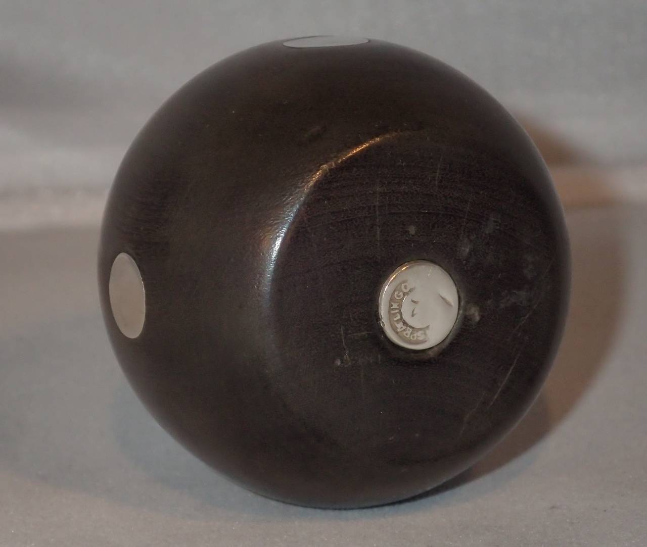 A charming ebony and silver inlaid polka dot motif candleholder by William Spratling. A carved formed sphere of ebony with four inlaid silver polka dots around the outer circumference and topped with an inset silver bowl shaped candle cup.
Stamp: