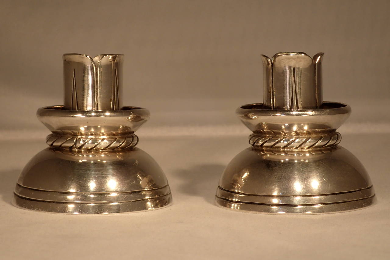 Pair of charming and beautiful small silver candle holders by William Spratling. Formed on a line-etched half sphere bulb base, pinched with a wrapped rope design and topped with a bowl and formed leaf or lily pedal candle cup.
Stamp: marked with