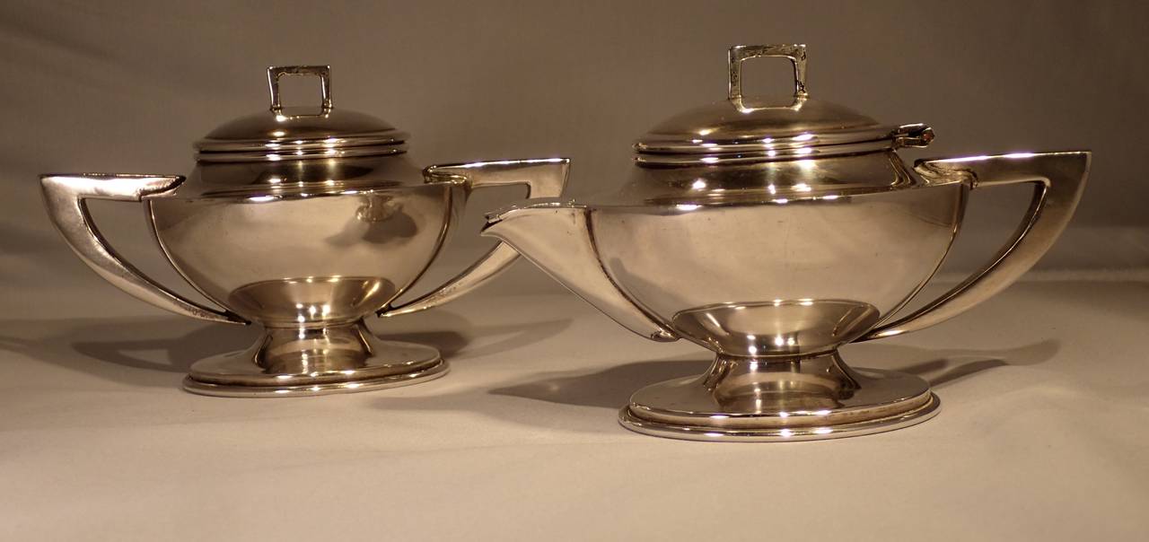 A beautiful art deco inspired silver European style cream & sugar service by Hector Aguilar. Formed with a genie lamp body set atop a circular disk base, each with elegantly curved and angular handles, topped with slightly mounded lids lifted by a