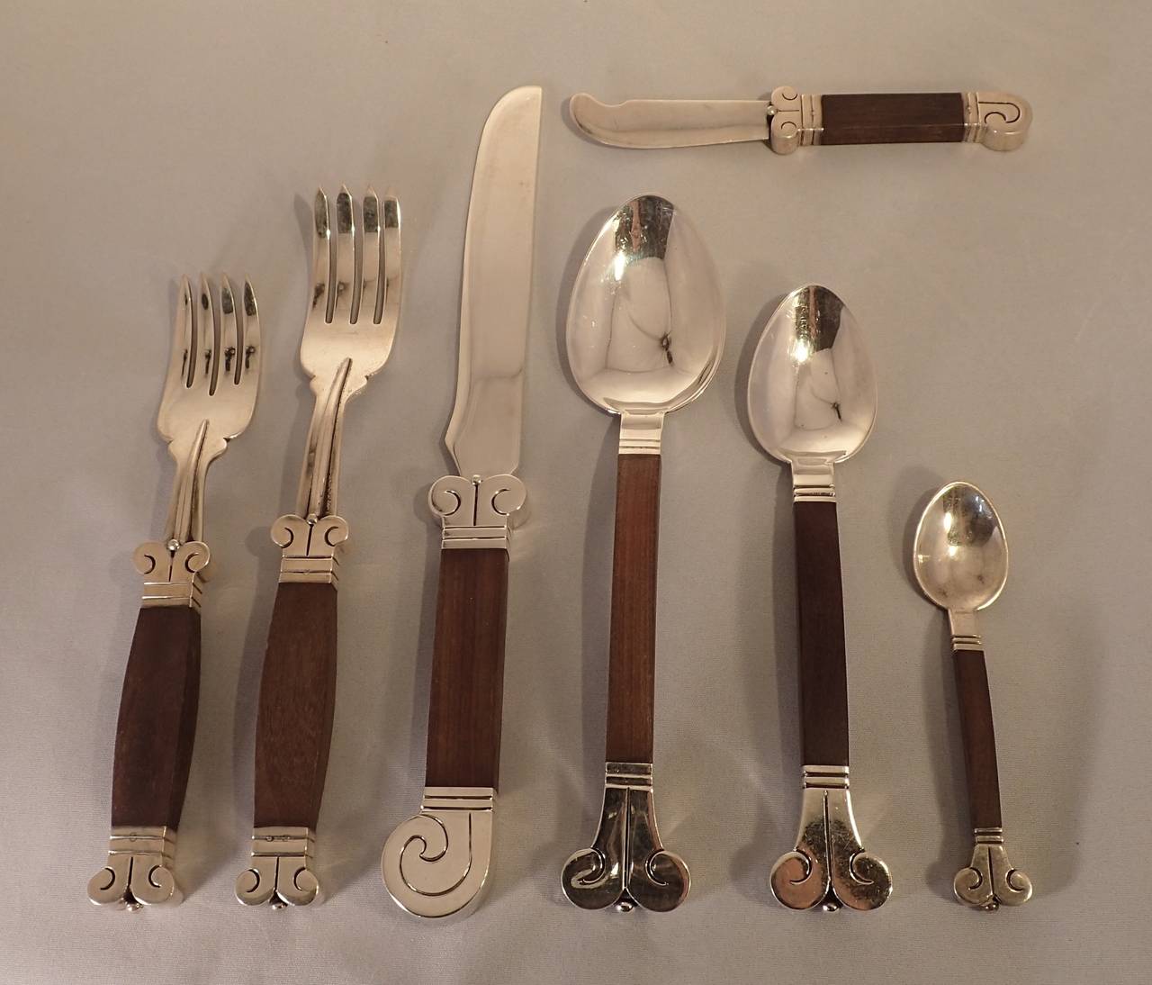 A rare and spectacularly designed and executed set of hand-wrought and carved silver and rosewood Aztec pattern flatware by Hector Aguilar. Comprised of four place settings, with seven pieces per place setting, each setting containing a salad fork,