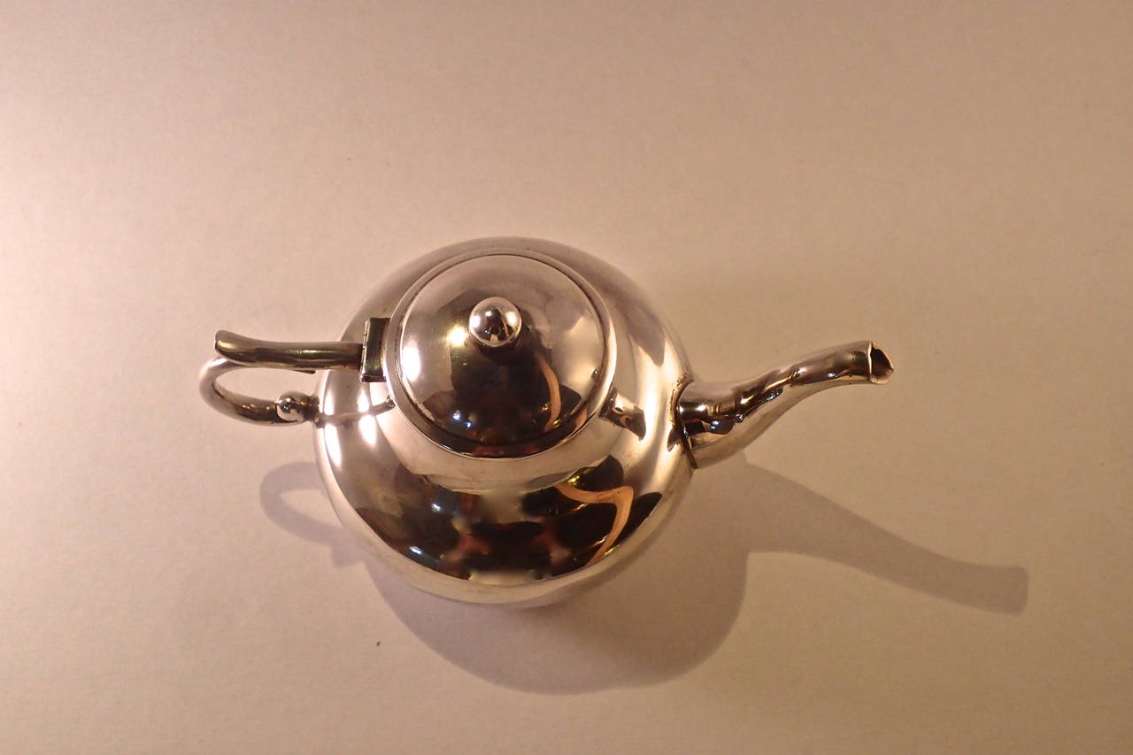 A beautiful silver teapot made by Hector Aguilar in the 1950s. 
This fine vintage sterling silver teapot has a circular compressed rounded form with an incredible and unique foliate handle. It is featured in the book 