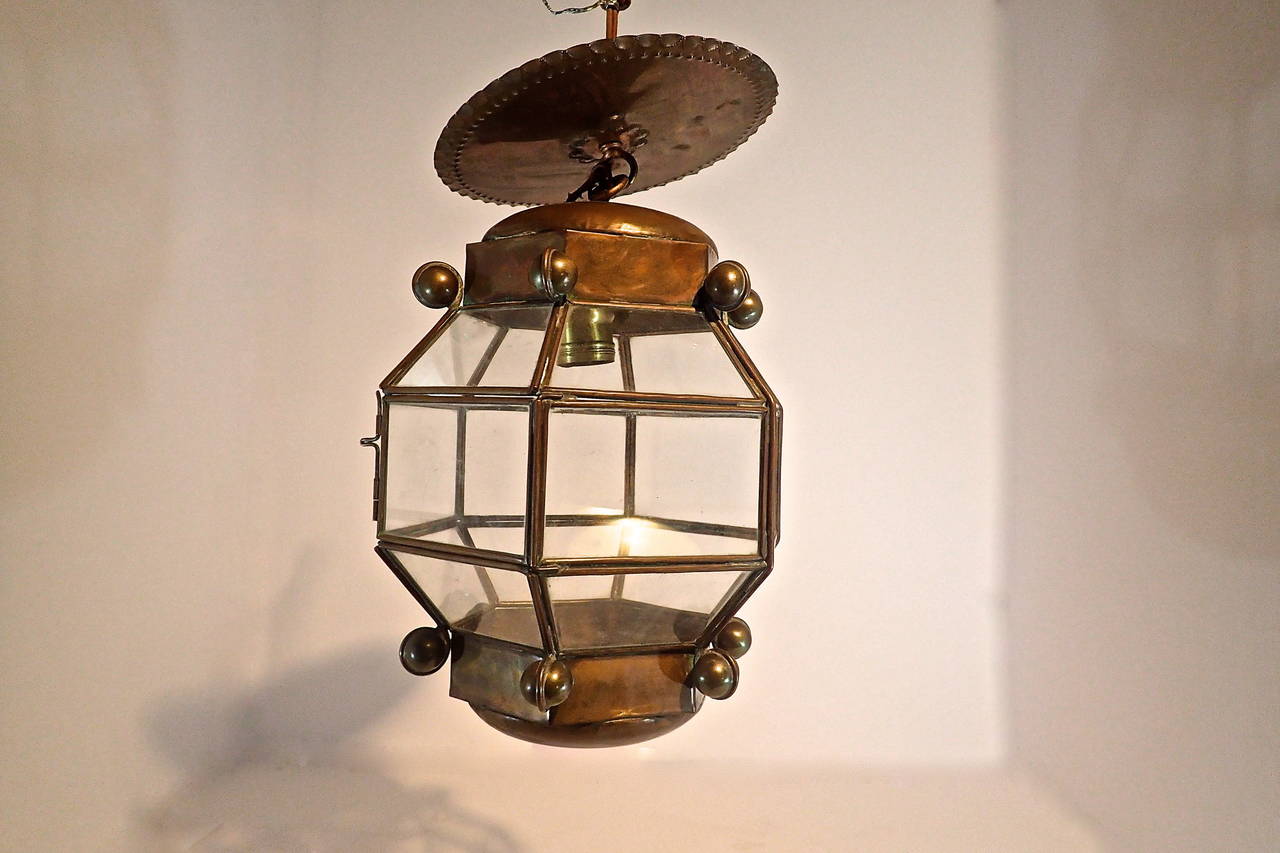A handsome copper and glass lantern by Hector Aguilar, circa 1945. A faceted hexagonal form in copper with glass panels, round top and bottom with repeating applied brass spheres, marked Hector Aguilar, Taxco Mexico.