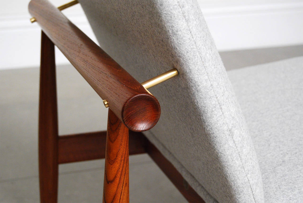 Finn Juhl's iconic 'Japan' chair with teak frame, wonderful exposed brass brackets and floating seat. The unusual frame was inspired by the Miajima water gate off the coast of Hiroshima and designed in 1953. This is one of Finn Juhl's most sought