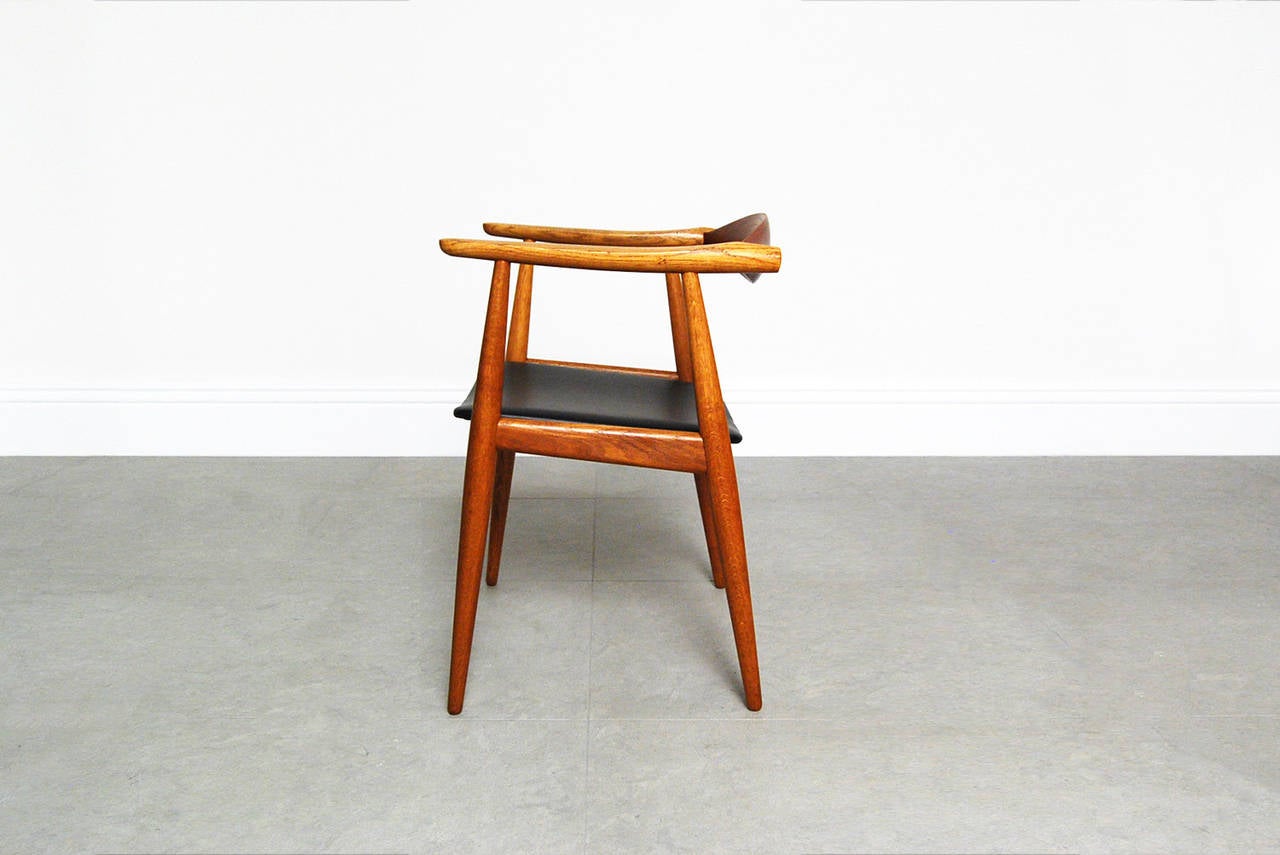 Stunning armchair designed by Hans Wegner for Carl Hansen & Son, circa 1960. The frame is made of oak with contrasting teak back support. The seat has been recovered in soft black leather.