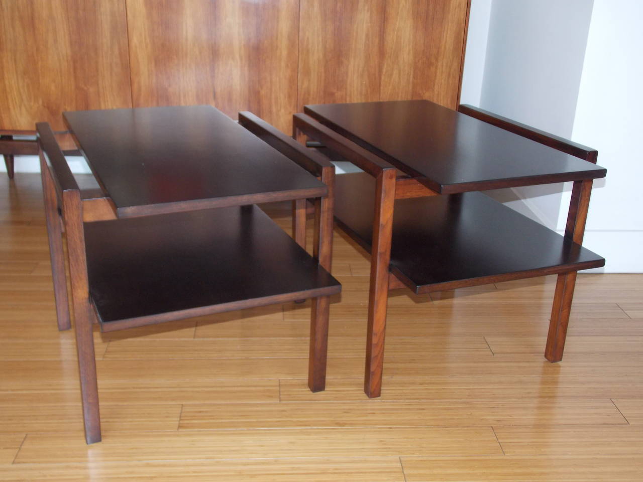A handsome pair of tables.
Manufactured by Glenn of California. 
Made of plywood shelves (no press-board) with walnut veneer and solid walnut base frames, with original screws.
They have been refinished with a nice moca stain.
A timeless design