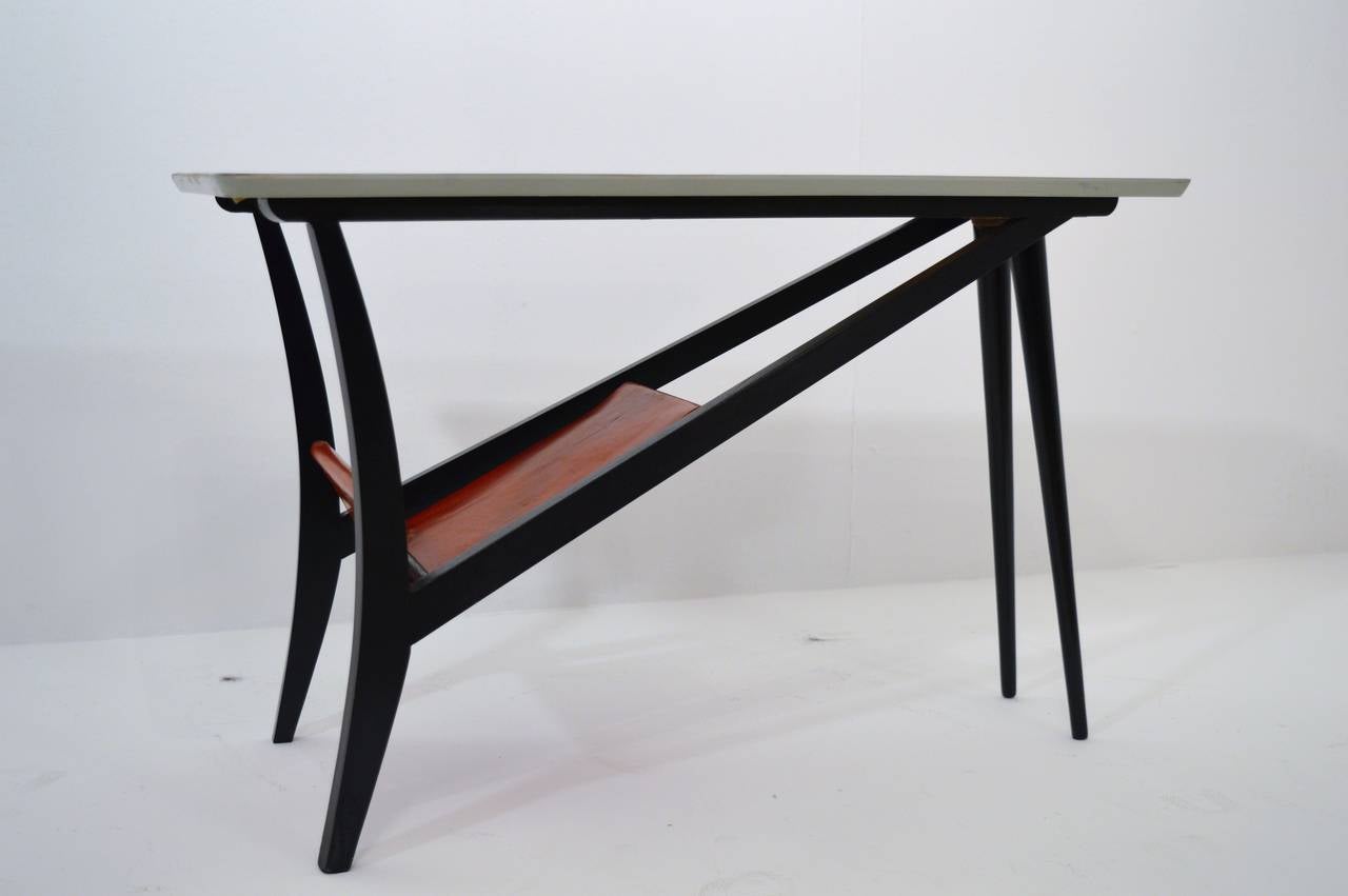 This sculptural coffee table was designed and manufactured in Belgium during the 1950s. The frame is made of black painted wood, while the top is made in white laminated formica. The magazine-rack is in red leather.
Very good restored condition.