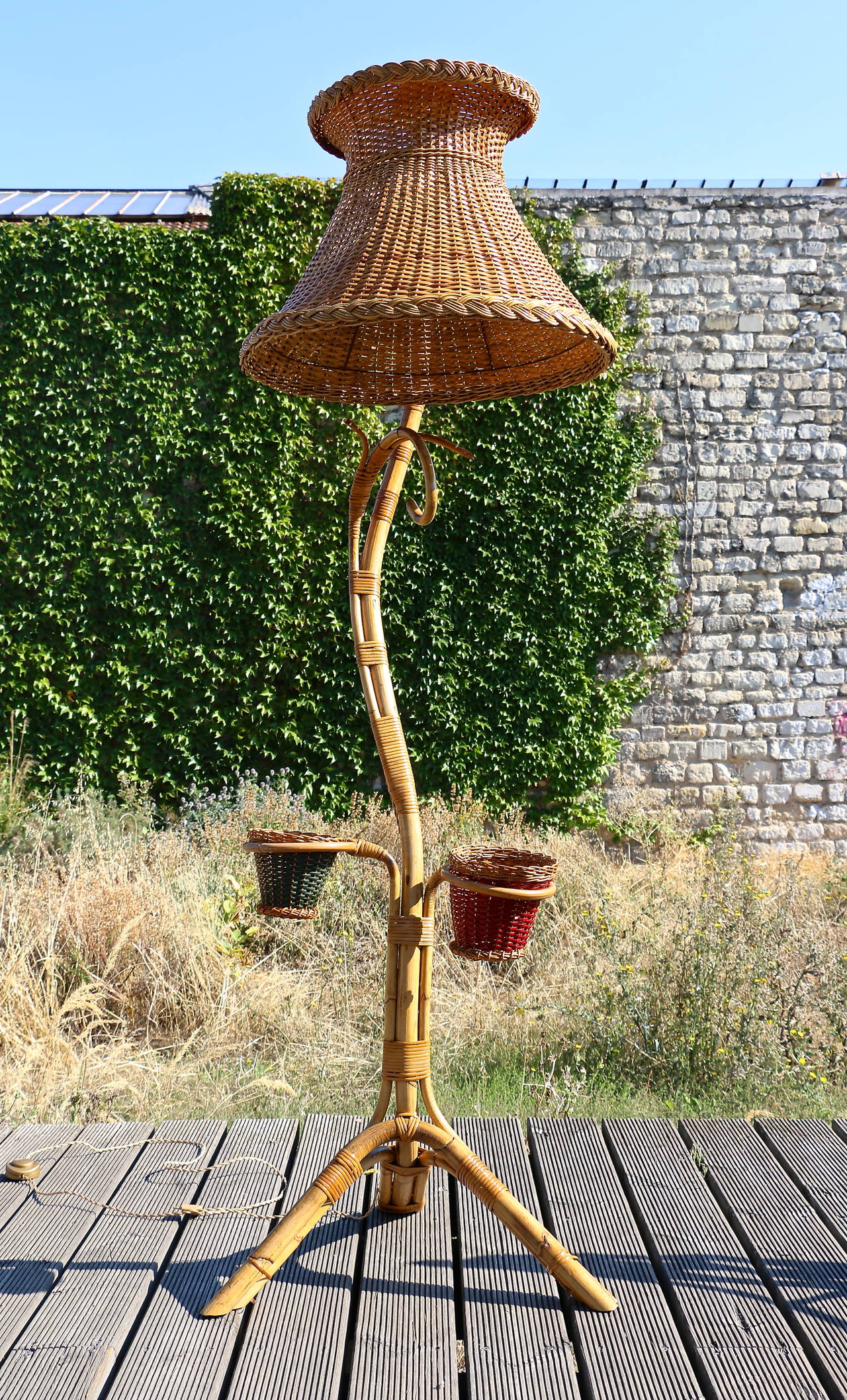 Tall floor lamp in bamboo with lampshade and two small rattan planters.