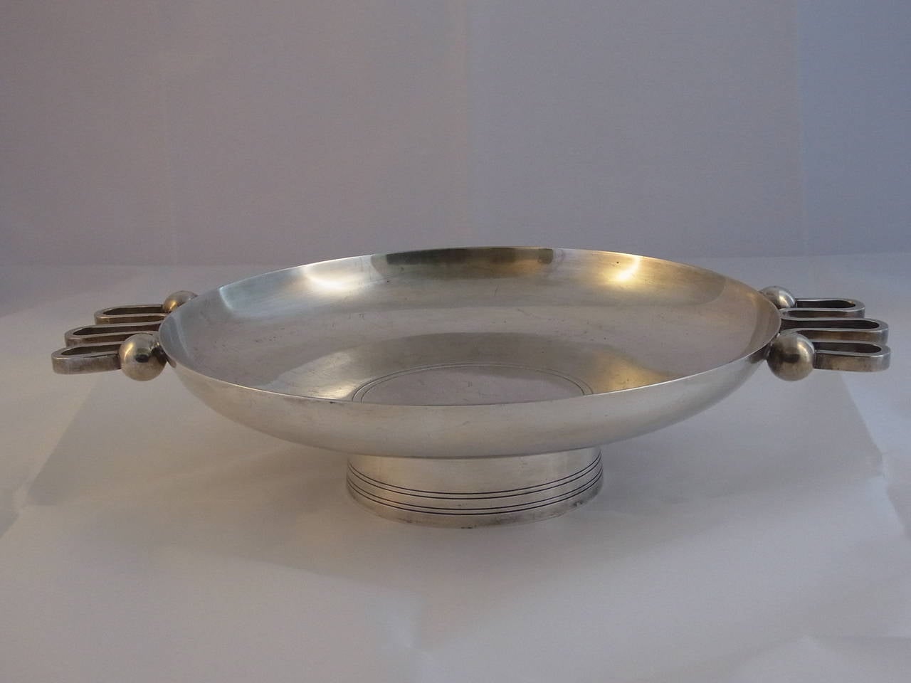 Round flat silvered metal bowl with two convoluted handles with ball endings designed by Christian Fjerdingstad for Christofle. Model exposed at the 1940 Milan Triennale.
Rare model.
Christofle punch and stamp.

Bibliography: Anne Bony, 'Les