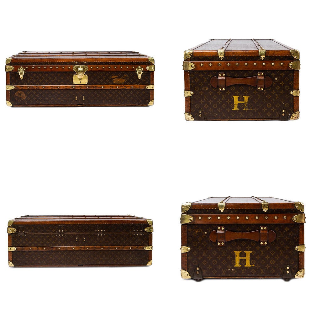 Antique 20th Century genuine and superb Louis Vuitton cabin trunk, large size, painted LV monogram canvas, composition leather and brass bound, reinforced with wooden laths, with wheels to the base and leather handles and stamped initial 