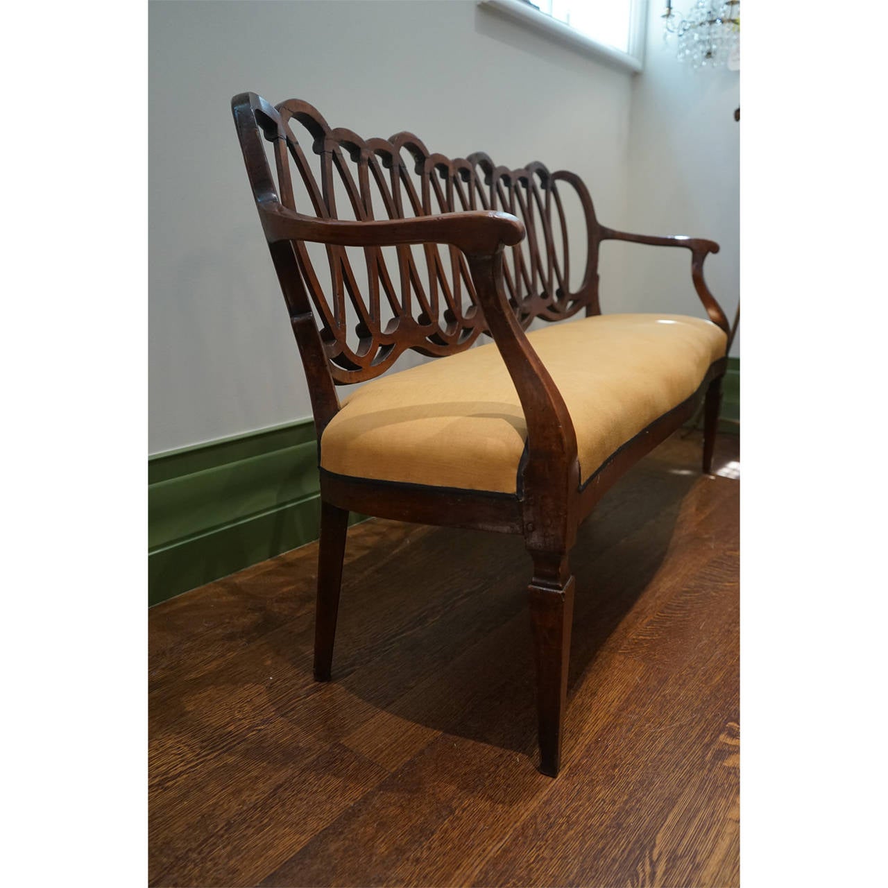 Italian neoclassical carved walnut settee with graphic infinity loop back. Newly upholstered in linen with grosgrain trim.