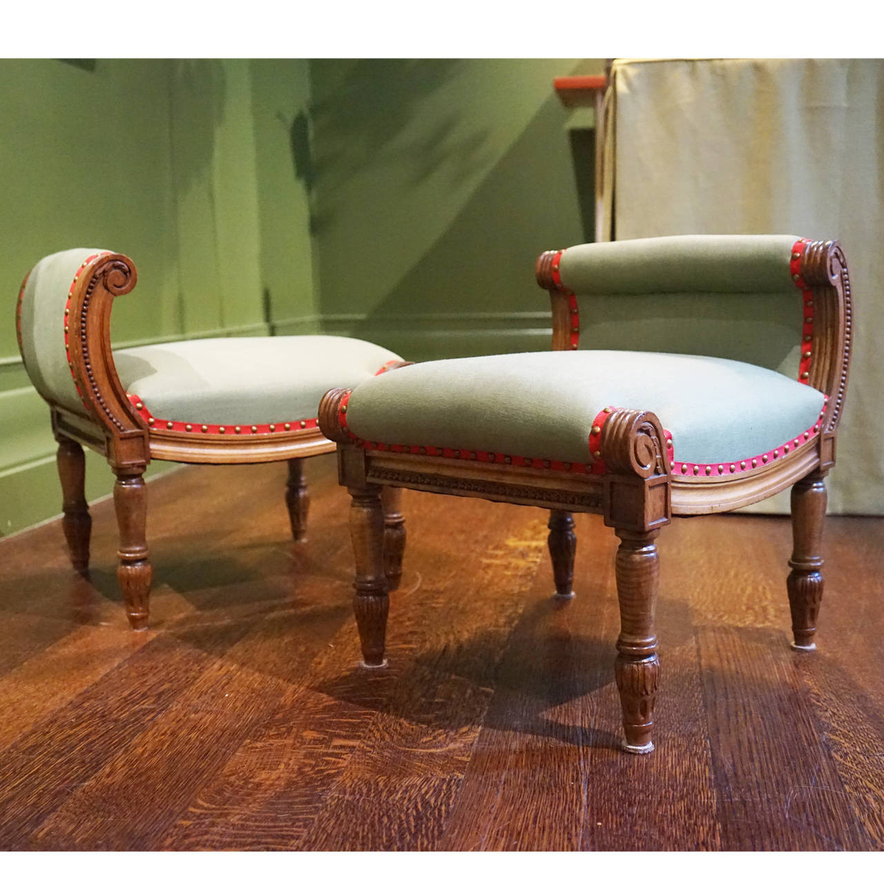 Pair of unusual 19th century French carved walnut footstools.  Detailed carving, newly upholstered in linen with grosgrain trim and antiqued brass nail heads.