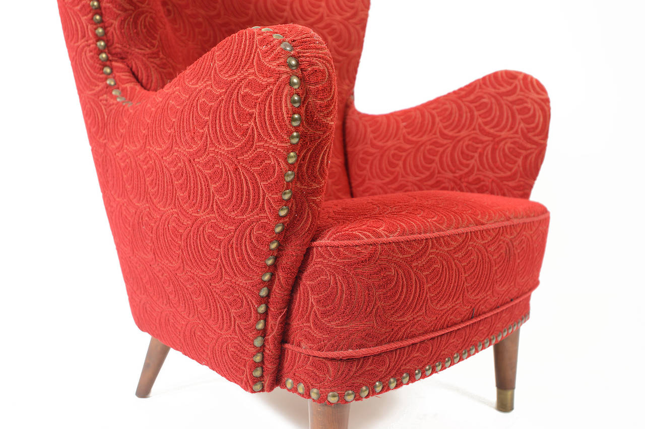 This elegant Danish club chair features sculpted curves adorned with brass studs, elm spindle legs, and brass ferrules. Covered in original crimson swirled frieze upholstery, this chair is a true icon of the 1940s. In excellent original condition