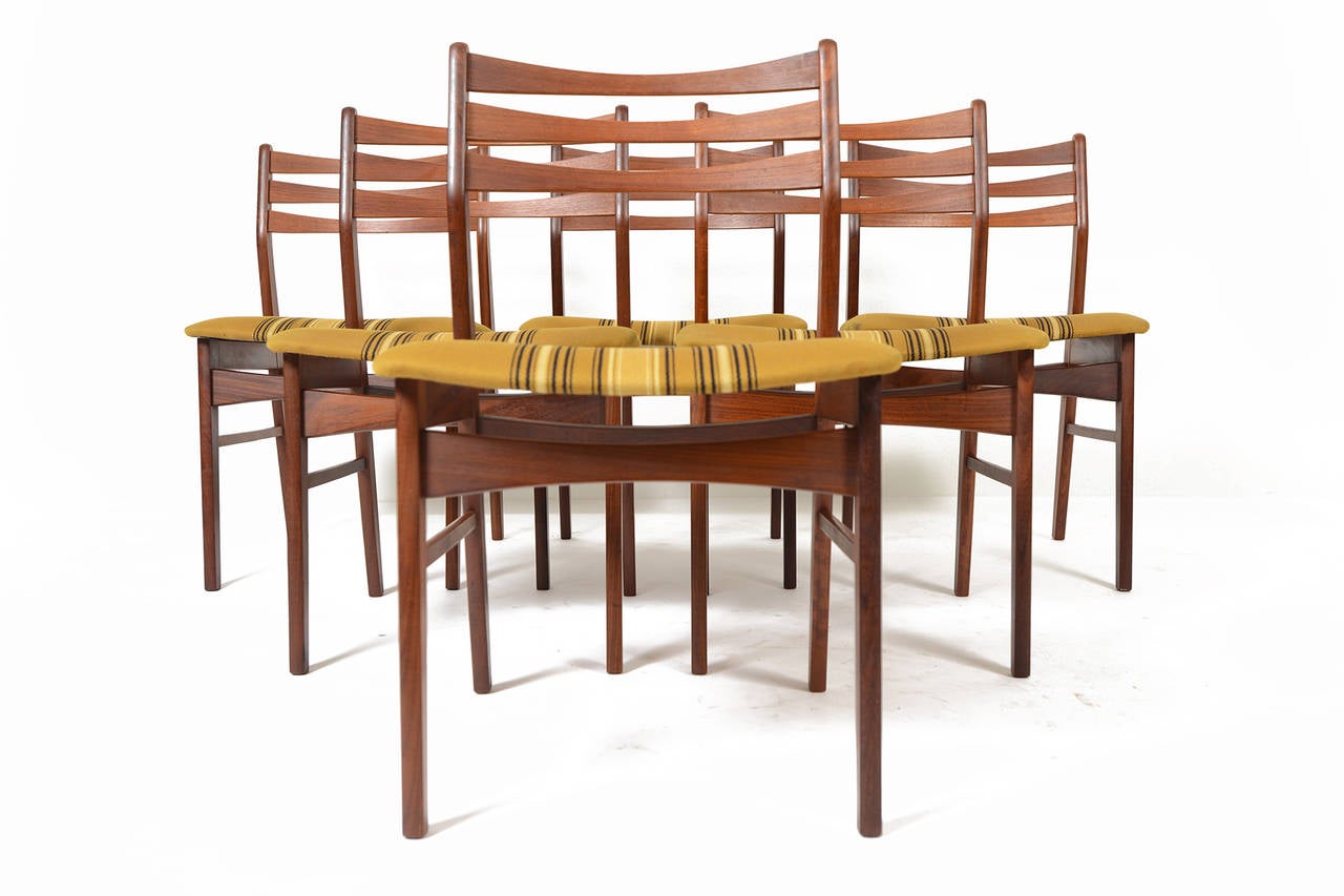 This set of six teak ladder- back dining chairs was manufactured by Findahls Møbelfabrik in the 1960s. Each backrest is crafted with three, bent teak slats that are as elegant as they are ergonomic. Seat bottoms feature their original mustard and
