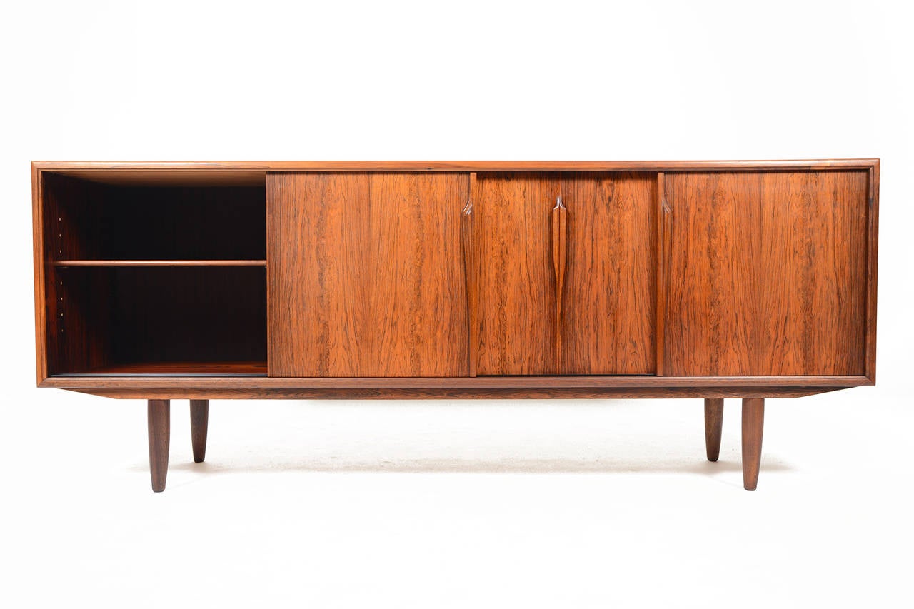 This high end Danish modern mid century credenza was designed by Axel Christensen for ACO Møbler. Crafted in Brazilian rosewood with handsomely refined lines and executed with an expert level of craftsmanship, the two sliding doors open to reveal