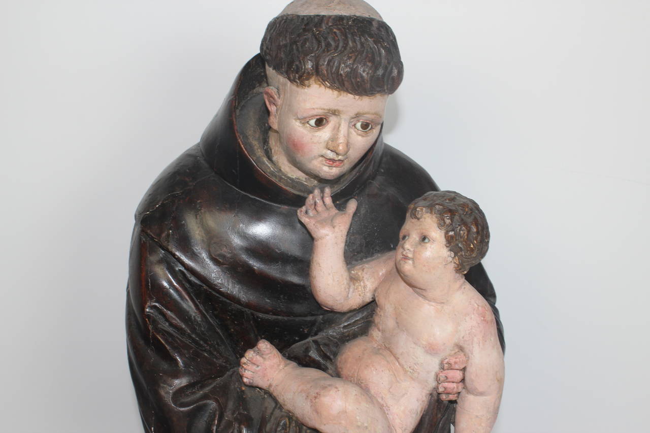 19th century St Francis wearing a rob with rope tied around his waist. Holding with two-arm a child.