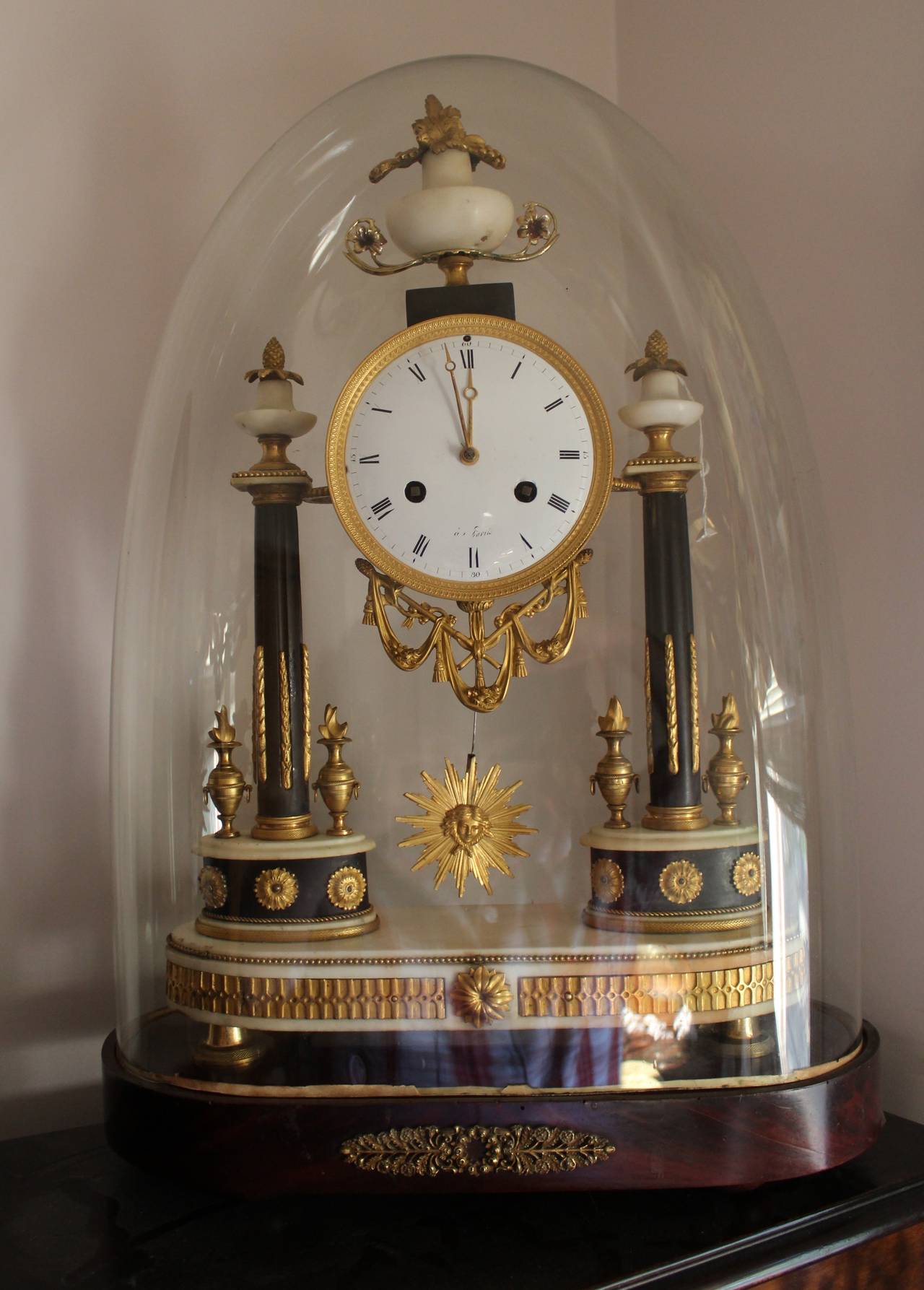 Early 19th century French Empire period marble and ormolu clock.

French Carrara marble Portico clock with extensive ormolu fretwork mounted on two finely decorated marble columns topped with three ornate ormolu finials shaped as pineapple topped