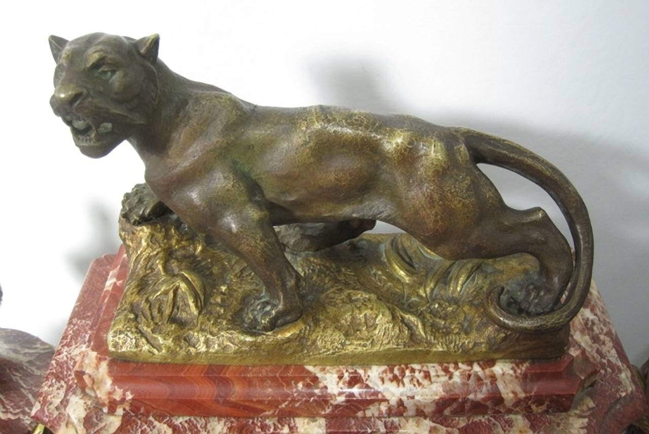 Französische Marmoruhr und Garnitur im Stil Louis XVI.

Regulatoruhr aus Kristall mit Marmorsockel und -säulen, überragt von einem Panther aus Bronzeguss, signiert Rousseau. Begleitet von zwei Marmorurnen mit Akzenten aus