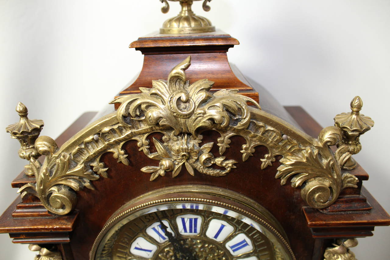 German Lenzkirch mahogany and carved ormolu cased mantel clock. The clock has wonderful carved scrolling feet supporting a rolled ridged stepped base decorated with leaf carved ormolu mounts. Running up the sides of the clock flanking the dial are