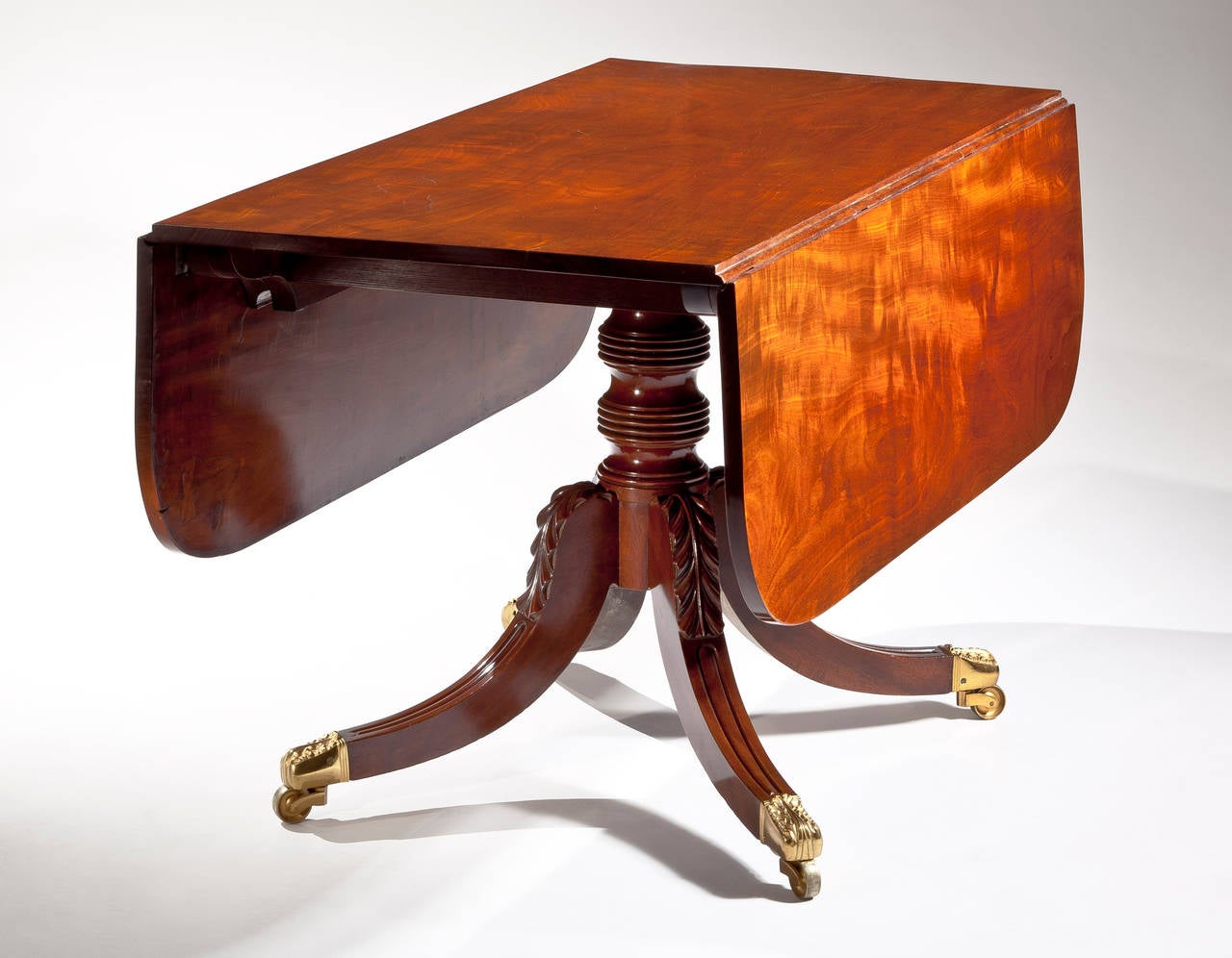 Attributed to Duncan Phyfe (1770-1854),
New York, circa 1820.

The figured solid mahogany top with D-shaped drop leaves on a single ring-turned pedestal raised on saber legs with distinctive acanthus carving at the knees, terminating in elaborate