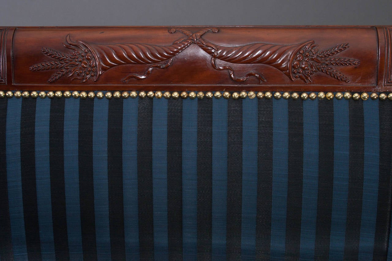 In the manner of Duncan Phyfe (1770-1854),
New York, circa 1815.

The scrolled crest rail with a central panel with relief-carved intertwined cornucopia issuing fruit and wheat, flanked by panels with carved 
