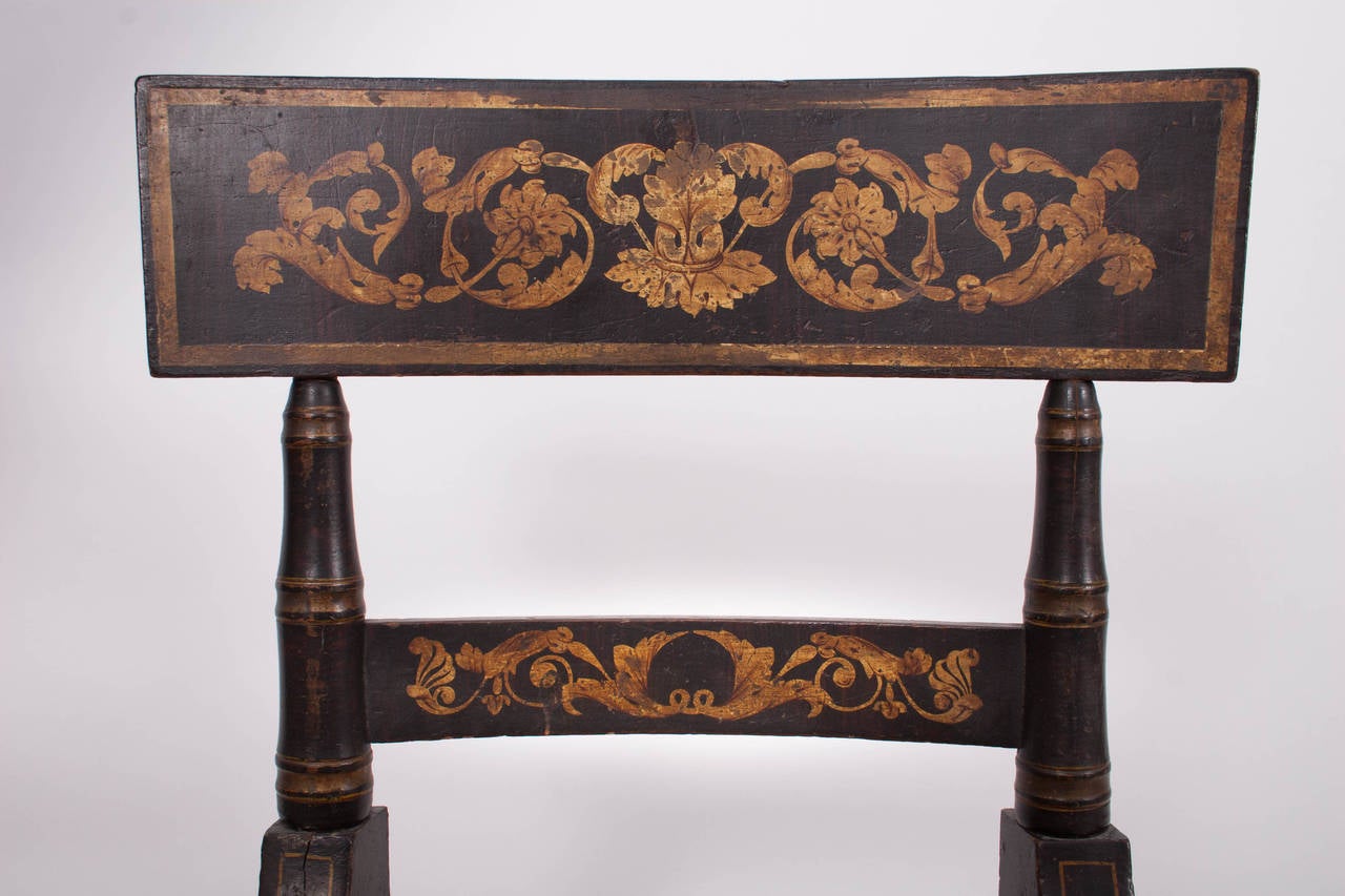Baltimore, circa 1830.

Each with tablet crest faux-grained a gilt-stenciled with foliate scrolls, the turned styles holding a stenciled stay-rail and continuing to a rush seat above turned, tapering front legs punctuated with gold-painted bands