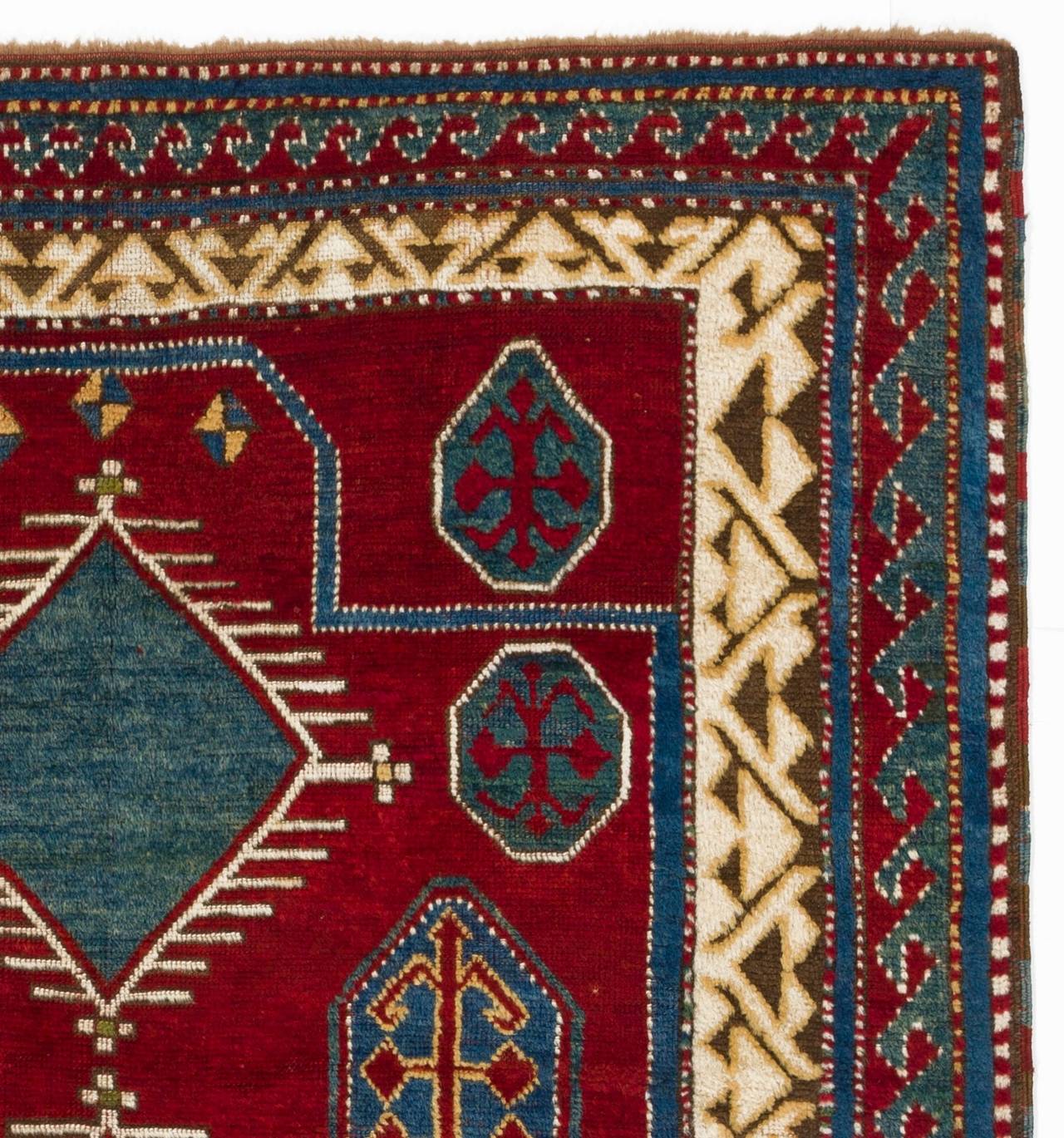 A great harmony of natural red, blue, cream and green colours is seen on this skilfully woven collector`s rug from South West Caucasus depicting a bold and powerful geometric design, well balanced on a crystal clear madder red ground. Full soft wool
