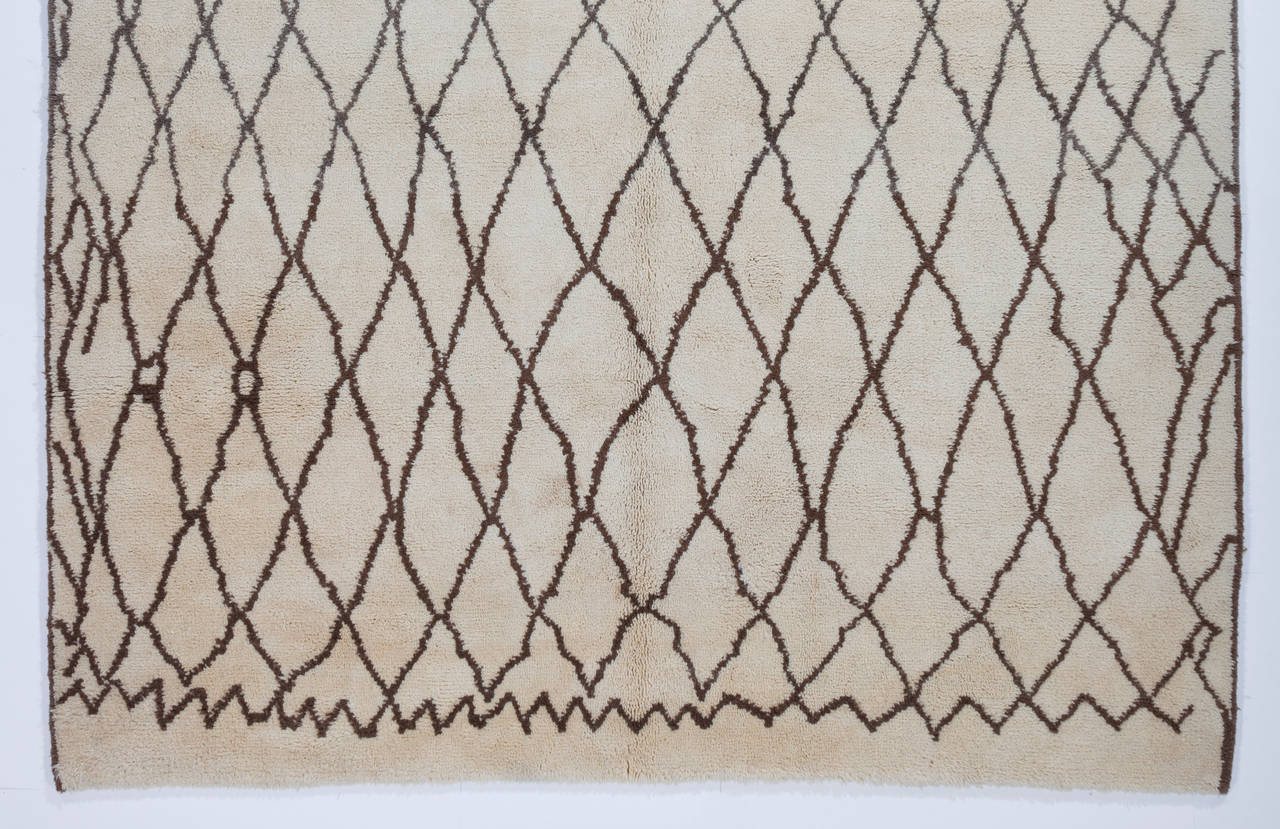 A modern handmade Moroccan rug made of natural undyed ivory/cream and brown sheep wool with a touch of natural-dyed red at the bottom end. 
The rug is available as it is or made to measure in any size and color combination requested.