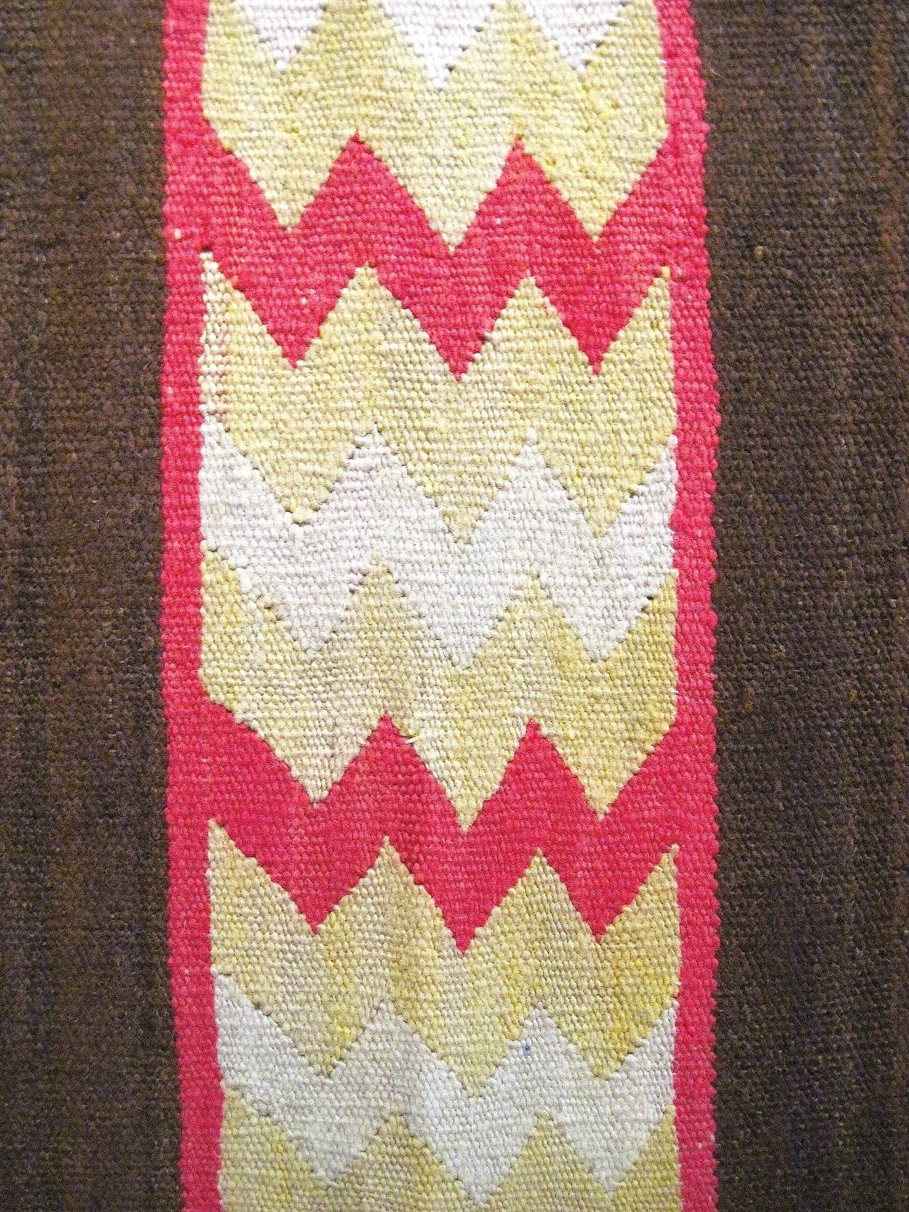 This intensely graphic and colorful small Navajo weaving has been described as a child's wearing blanket; although it’s exact purpose may be up for discussion. Whatever its intended use might have been originally, today it can be appreciated for its