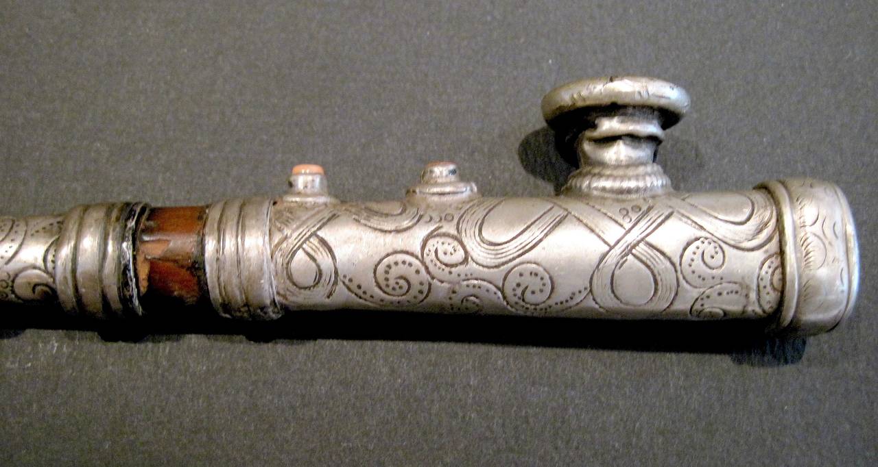 Beautiful, rare and elegant, this antique Tibetan silver opium pipe is hand chased with classic a motif, embellished with coral beads and has a bamboo heat barrier. Most pipes of this type found today are reproductions, as genuine, authentic pieces