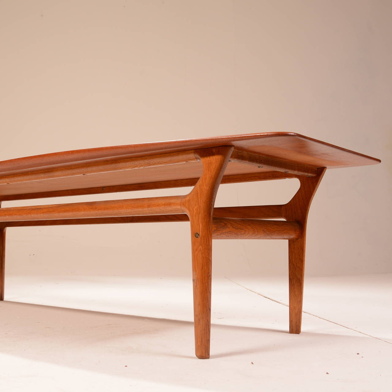 This is a solid teak and oak coffee table attributed to Kurt Østervig for Jason Møbelfabrik of Denmark and imported by Gunnar Schwartz Co. of Los Angeles. This large coffee table is in great vintage condition with no visible wear.
