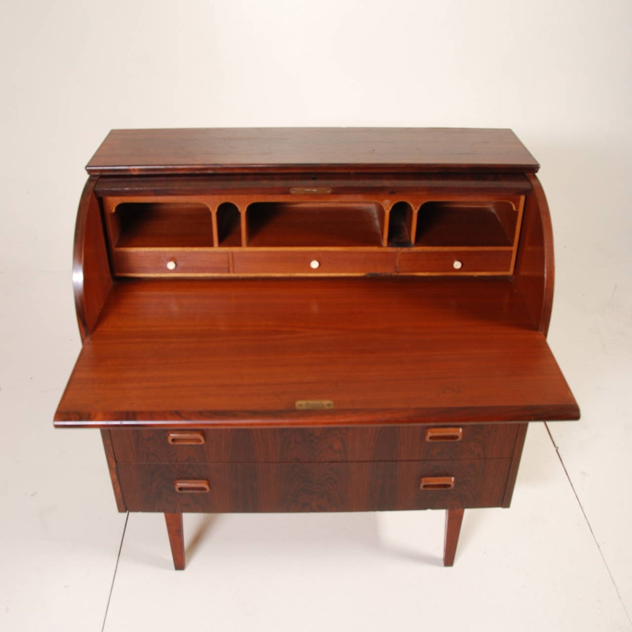 This mid century Swedish modern rosewood desk with a locking roll top is in good vintage condition with minor wear. It includes 3 large storage drawers and multiple cubbies and small drawers. Signed.