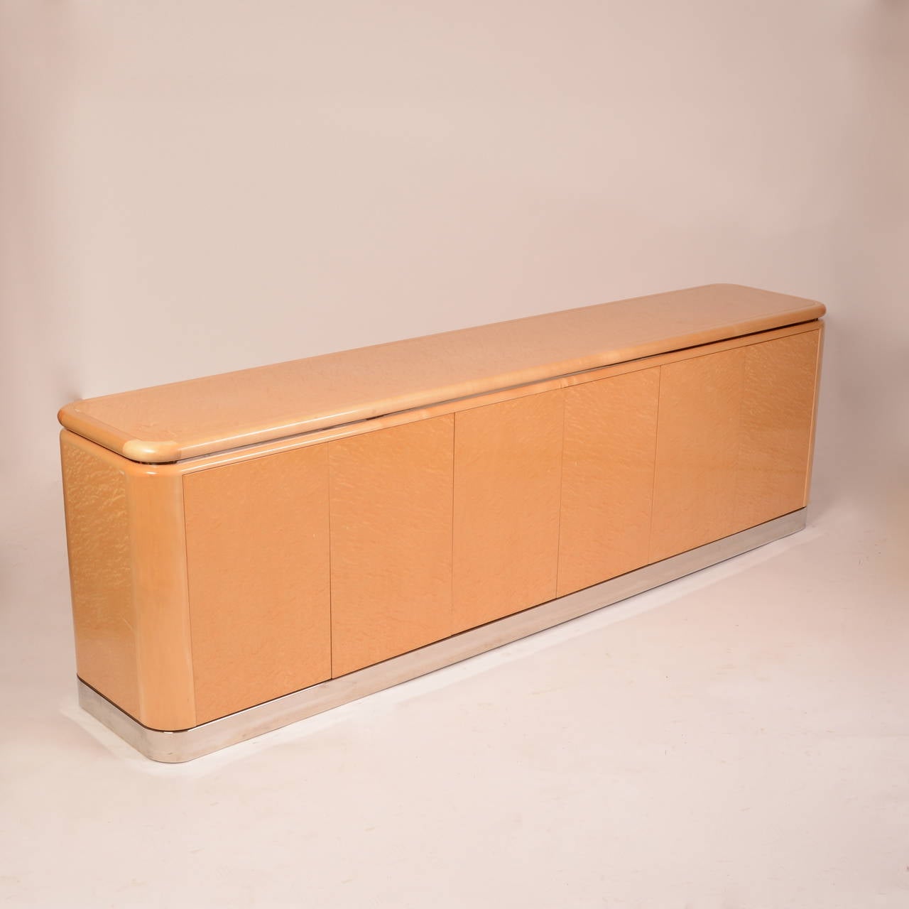 A beautiful 8' long credenza designed by Stanley Jay Friedman for Brueton with a polished stainless base, six doors, adjustable shelves, storage drawers and a finished back. This piece is in excellent condition with almost no wear.