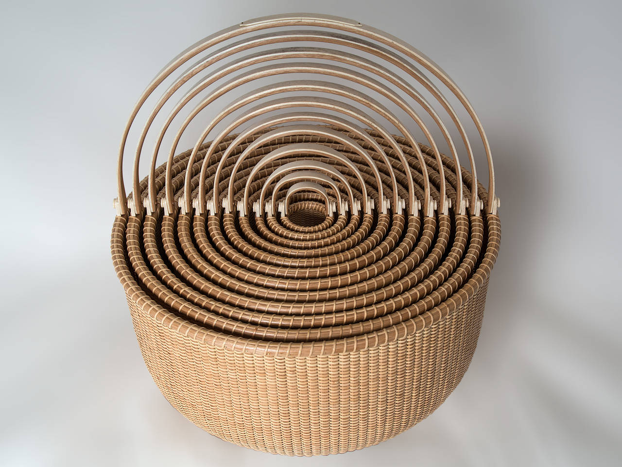 Exceptional nest of 12 Nantucket graduated baskets by noted Nantucket artists Bill and Judy Sayle. With hand cut oak staves, delicate antique bone ears and overlaid handles. The bases are turned out of Mahogany. The largest basket measure 18 1/2