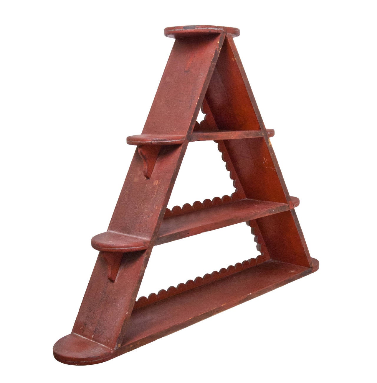 A painted pine hanging shelf in unusual triangle form with scalloped surround, retaining its original red paint.