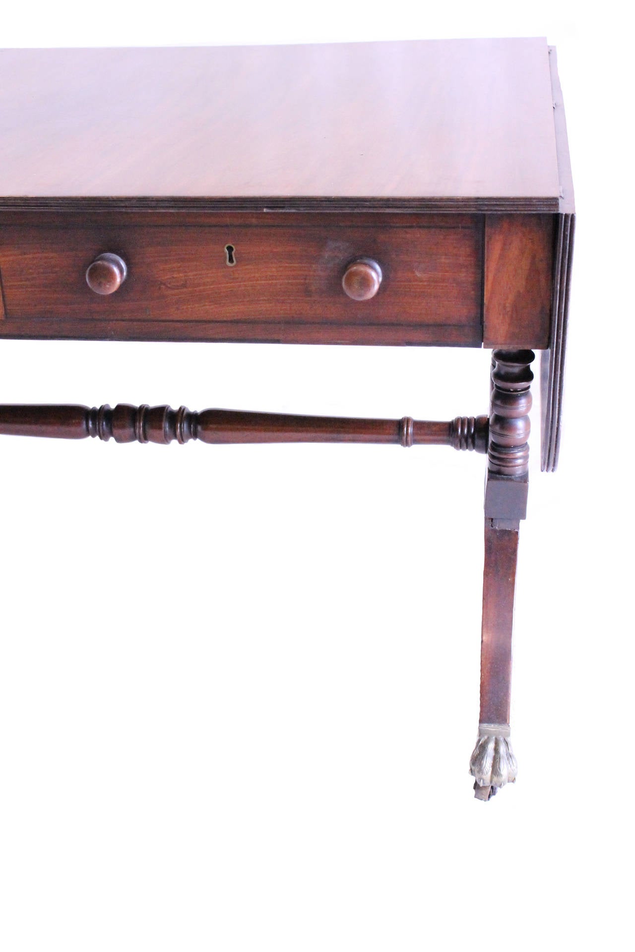 19th century Mahogany supported by turned legs ending in brass ball and claw feet. Turned mahogany stretcher. Table has two drawers with wooden knobs and two drop leaves.
