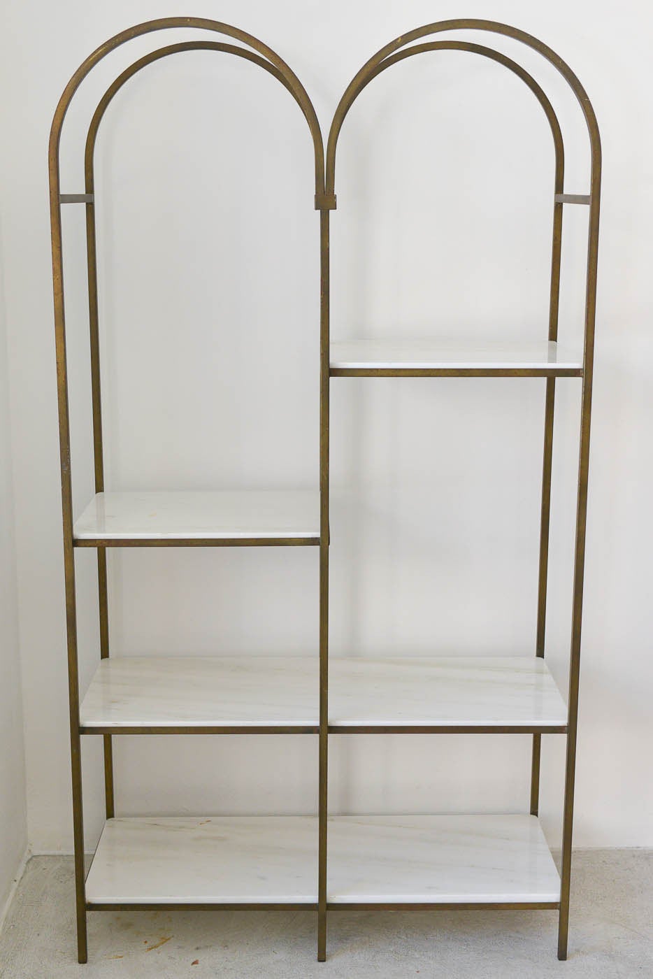 This beautiful Hollywood regency iron and white carrera marble etagere by Frederick Weinberg has 4 shelves, two half and two full, staggered on opposites for added balance and appeal.

Beautiful iron arched framing and solid construction, the