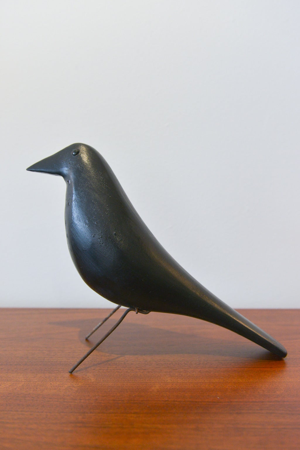Vintage hand carved wooden crow decoy attributed to Charles Perdew of Illinois.  This vintage bird has glass eyes, wire legs and is hand carved.  

Came from an estate in Central Illinois, the 'Eames House Bird' is an iconic piece of mid century