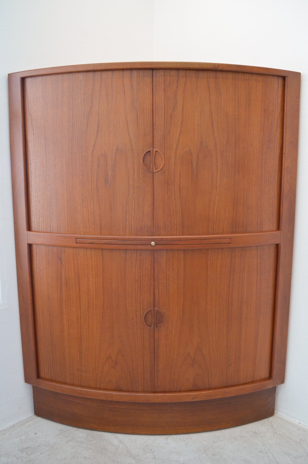 Unique tambour door corner bar in teak has been professionally restored and in excellent condition. Both upper and lower compartments have teak tambour doors that slide perfectly.

Upper section has two adjustable shelves with black laminate to