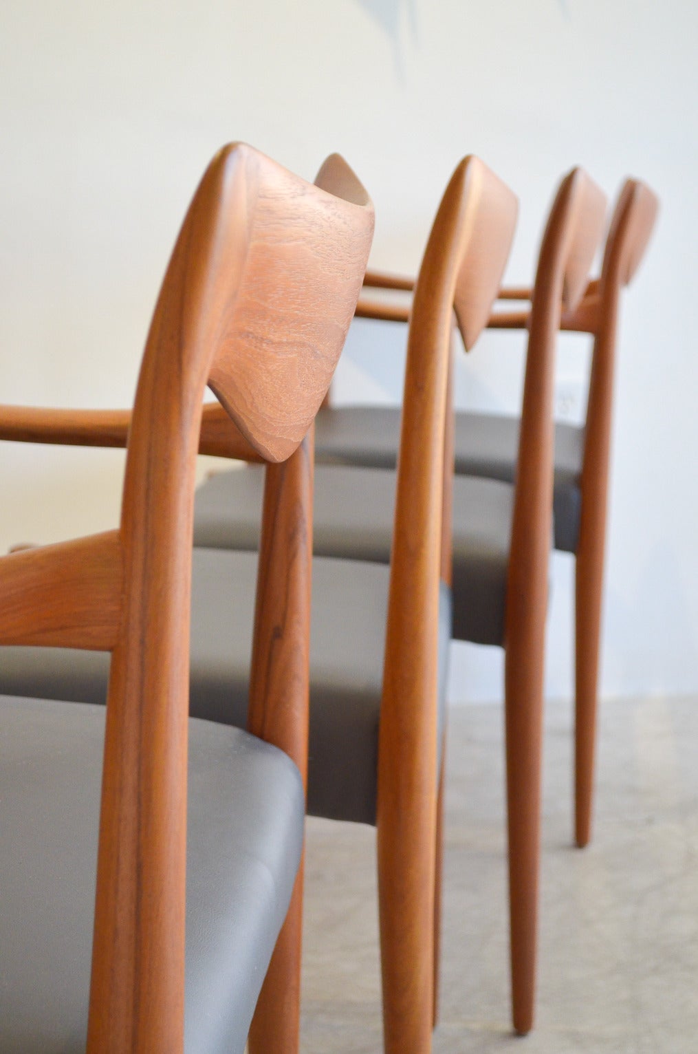 Beautiful set of 4 hand sculpted teak dining chairs by Rolf Rastad and Adolf Relling for Gustav Bahus of Norway.  Set includes two armchairs and two side chairs. Quality craftsmanship with hand sculpted arm and backrests with newly recovered grey