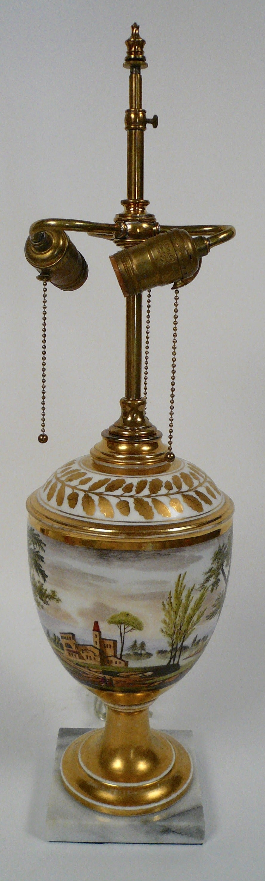This Old Paris porcelain urn is hand painted with figures in a landscape, has a marble base, and dates from the mid-19th Century.