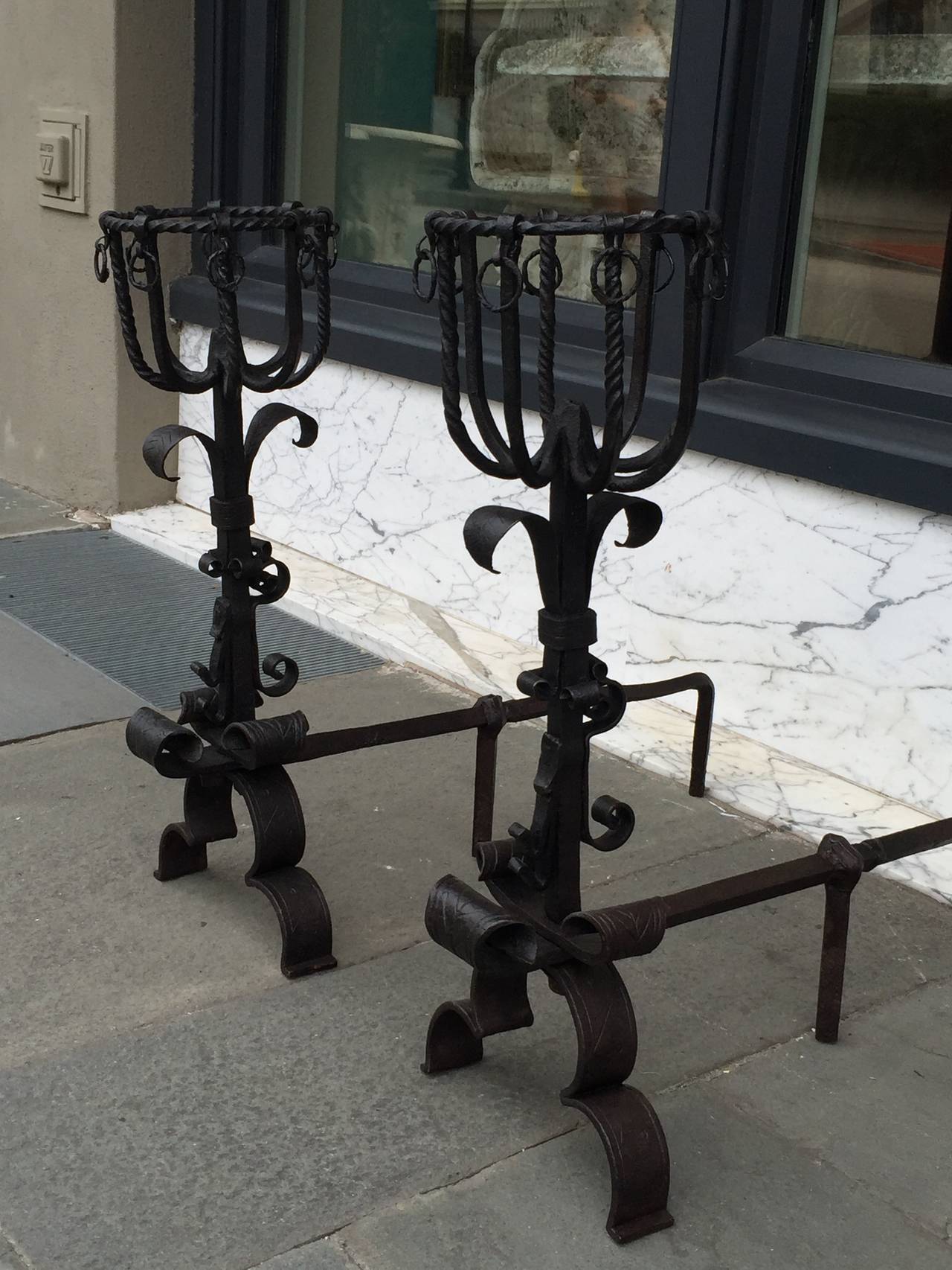 Pair of ornatlely detailed continental andirons with scrolled iron work around the feet and basket tops circa 1840 